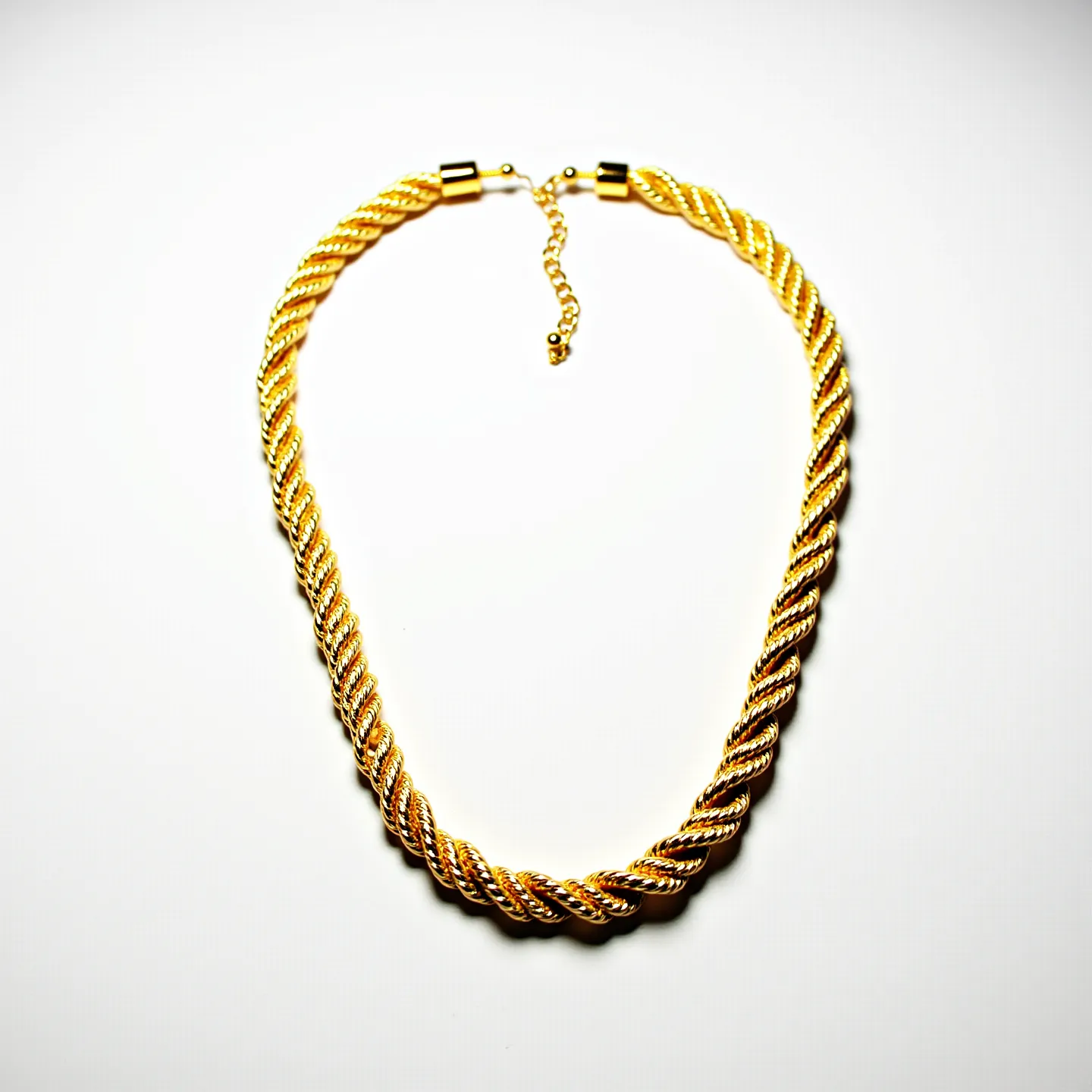 This gold rope necklace features intricately twisted strands of gold, showcasing a classic rope design that adds elegance and texture. The necklace is crafted from polished gold material, enhancing its lustrous appearance. It features a simple yet secure clasp mechanism at the ends, complemented by a short length of adjustable chain, offering versatility in wear. The overall appearance is bold and sophisticated, making it a statement piece suitable for various occasions.