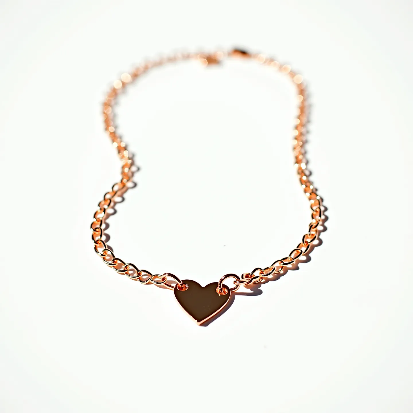 This heart chain necklace features a beautifully polished heart-shaped pendant seamlessly integrated into a chain of interlocking links. The necklace appears to be crafted from metal with a warm rose gold hue, giving it an elegant and contemporary look. The heart pendant is smoothly finished, adding a touch of simplicity and sophistication without any additional embellishments or stones. It is secured with a standard clasp that complements the overall design, ensuring both style and functionality in wearing.