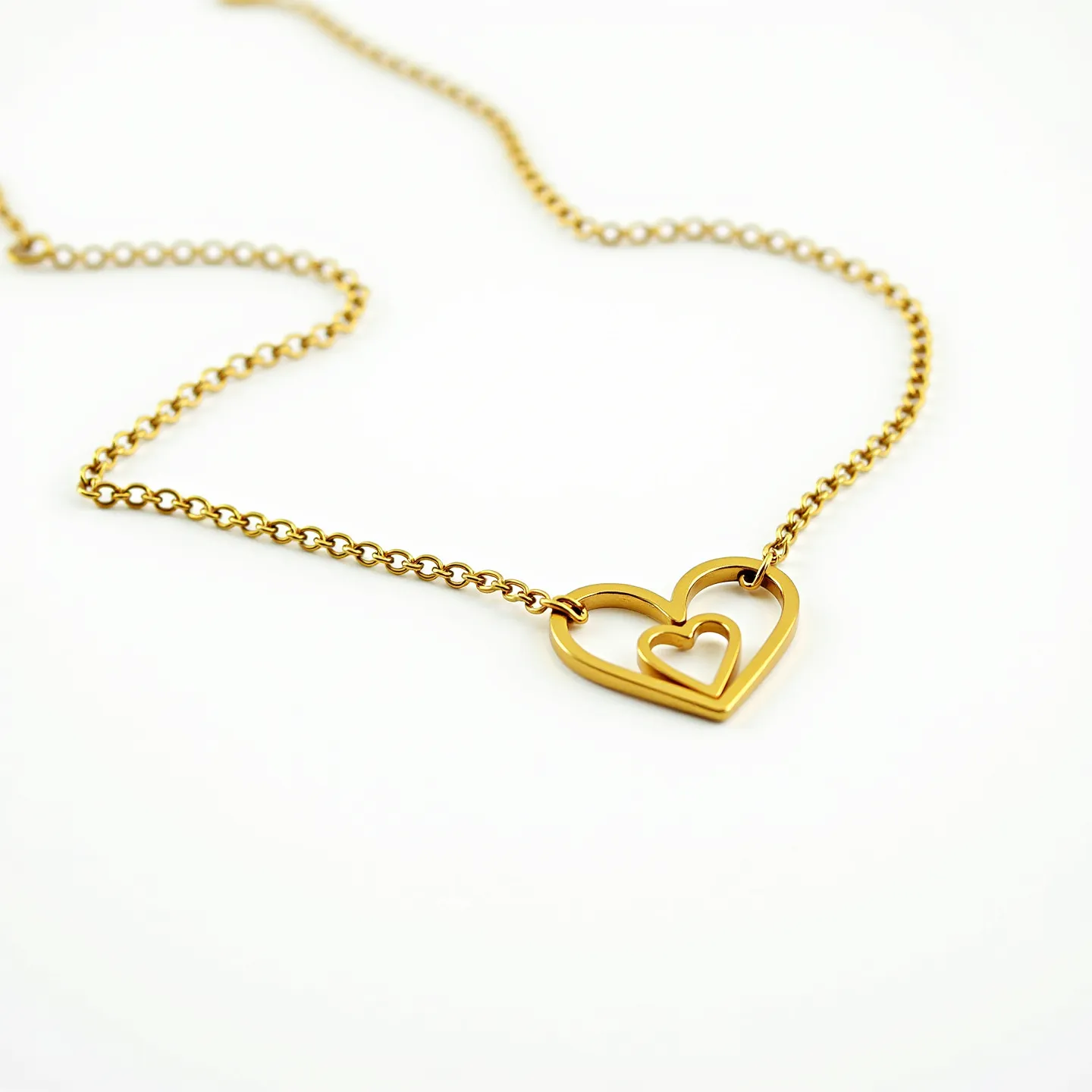 This heart chain necklace features a delicate design crafted from a gold-toned metal. It showcases a double heart pendant, with one smaller heart nested within a larger one, both having a smooth, polished finish. The necklace's chain consists of small, round links that complement the pendant's elegance and simplicity. The accessory is secured with a classic spring ring clasp, known for ensuring a reliable closure. The overall design exudes a timeless charm, making it a versatile piece suitable for various occasions.