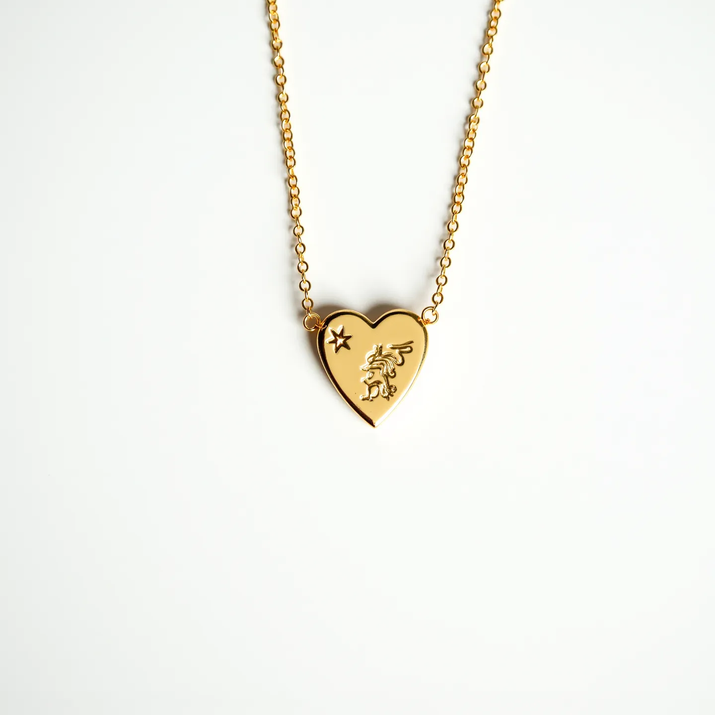 This heart chain necklace features a polished gold-tone heart-shaped pendant adorned with an intricate embossed design, including a star and a mythical creature, adding a touch of whimsy and elegance. The chain is composed of interlinked oval links that are smooth and reflective, complementing the pendant's gleaming finish. The necklace is secured with a lobster clasp, ensuring a reliable and easy-to-use attachment mechanism. The absence of gemstones allows the focus to remain on the beautifully detailed pendant and the warm luster of the material, highlighting its stylish and sophisticated appeal.