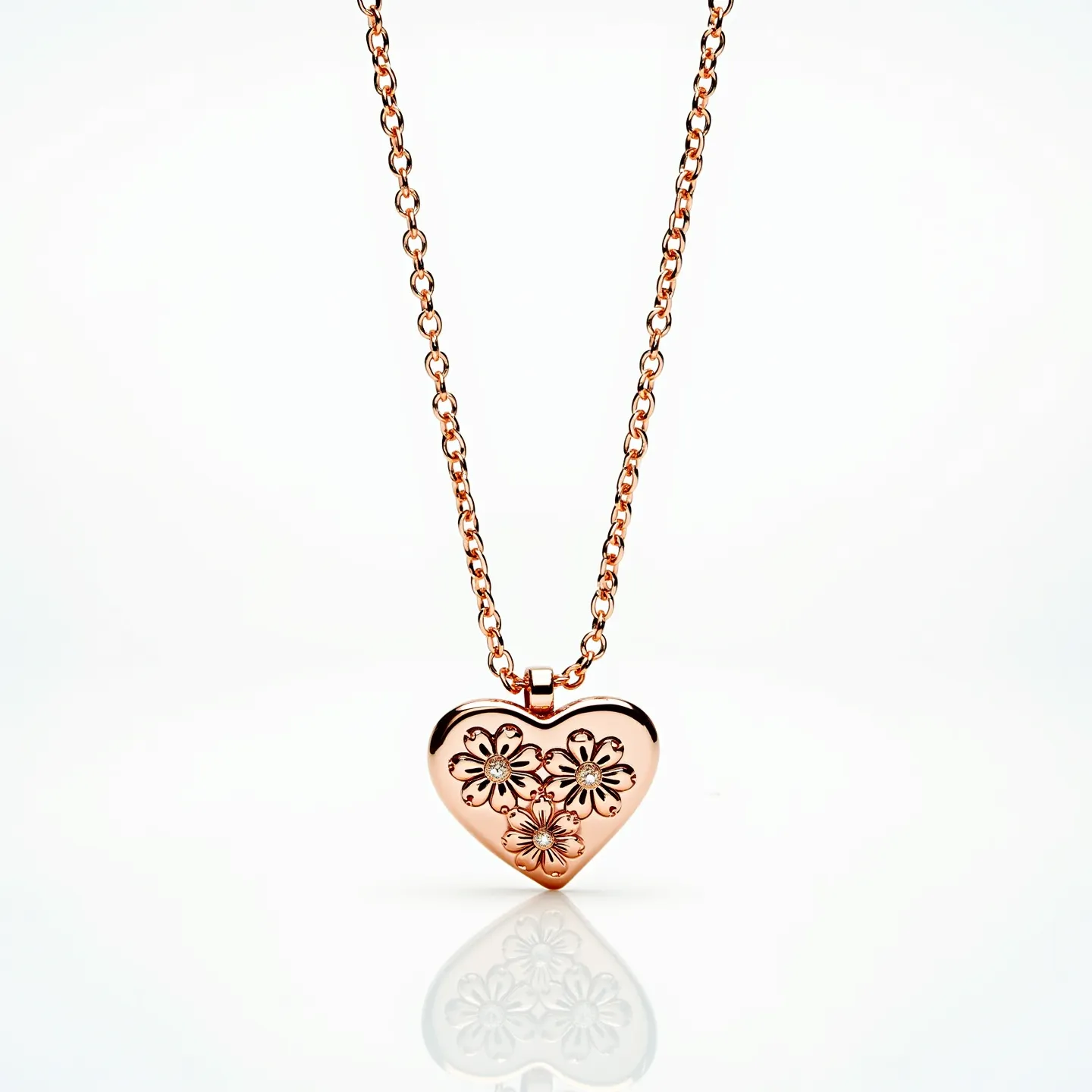 This heart necklace features a rose gold-toned metal with a delicate floral pattern etched onto the heart-shaped pendant, showcasing intricate craftsmanship. The pendant is suspended from a matching rose gold-toned chain, which complements the overall aesthetic of the piece. The chain is composed of uniformly sized links, contributing to a harmonious and balanced appearance. The attachment includes a standard loop that secures the pendant to the chain, ensuring stability and ease of wear. The design does not incorporate any stones or gems, focusing instead on the elegance and simplicity of the metalwork.