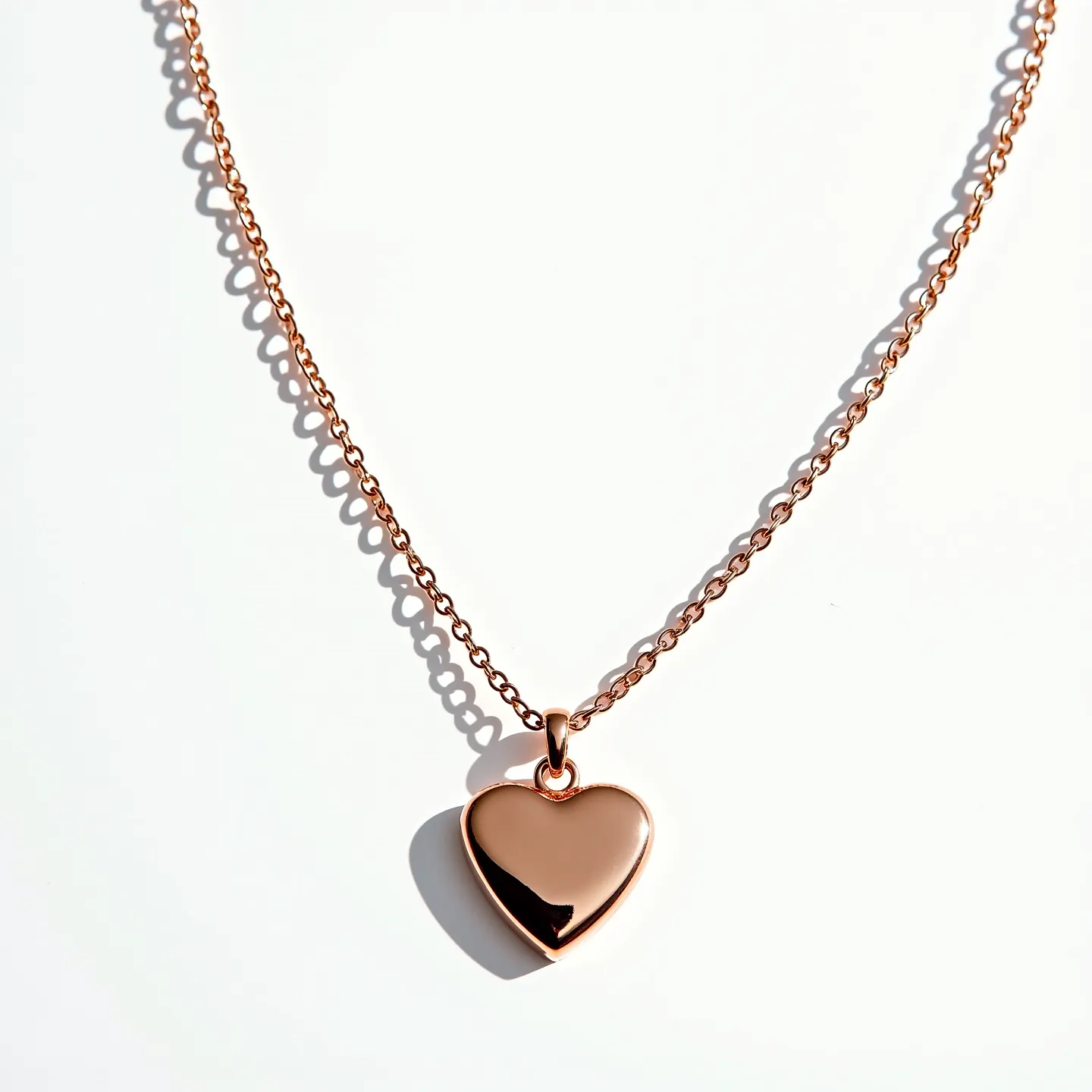 This heart necklace features a polished rose gold metal heart pendant, elegantly suspended from a matching rose gold chain. The chain consists of interlinked oval links, providing a delicate and refined appearance. The heart pendant has a smooth, glossy surface, enhancing its lustrous shine. The pendant is attached to the chain by a small, unobtrusive bail that offers seamless integration with the overall design. The chain is likely secured with a standard clasp, completing this elegant and timeless piece.