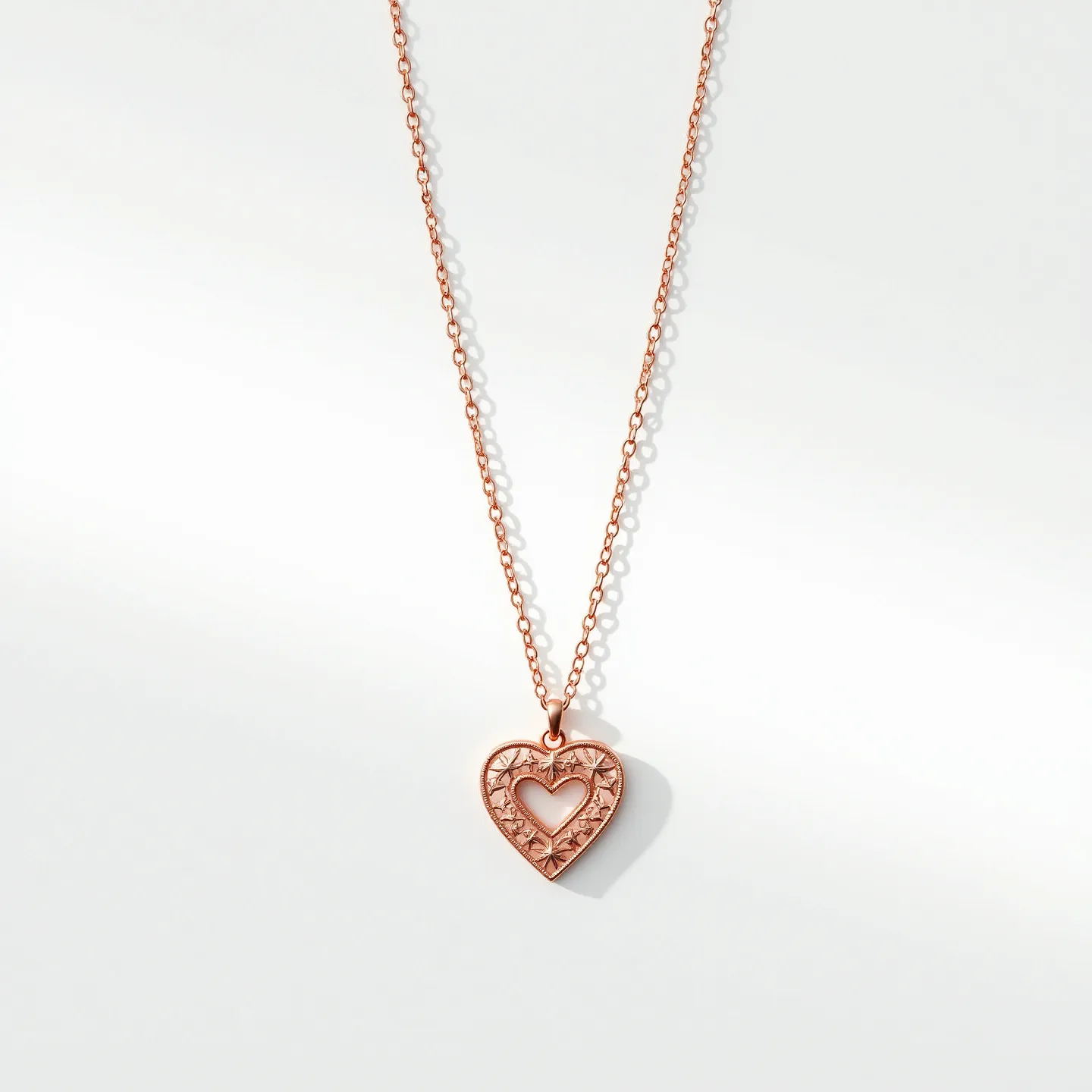 This heart necklace features a delicate rose gold chain with a pendant that takes the shape of a heart. The pendant is intricately designed, showcasing a smaller heart within the larger heart's open frame, embellished with subtle decorative patterns around it. The necklace includes a classic jewelry clasp for secure attachment. The combination of the rose gold and the intricate design gives it an elegant and sophisticated appearance.