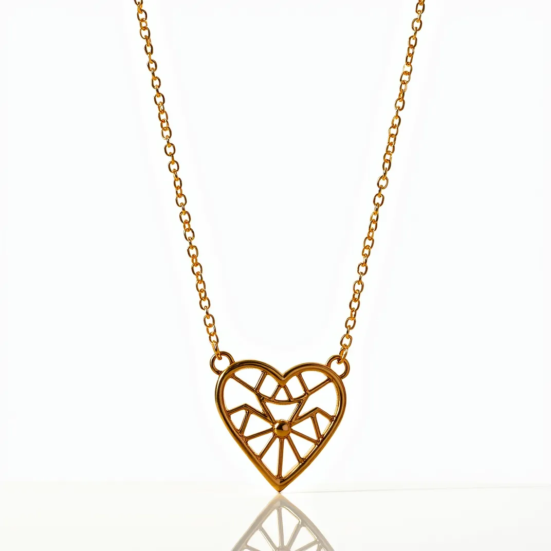 This heart necklace features a geometric openwork heart pendant crafted from a polished gold-toned metal. The intricate design showcases angular patterns within the heart shape, giving it a modern and artistic flair. The pendant is affixed to a delicate chain made of matching gold-toned links, providing a seamless and elegant look. The necklace is likely secured with a standard clasp, ensuring it can be worn easily and securely. Its minimalistic yet eye-catching design makes it a versatile accessory for various occasions.