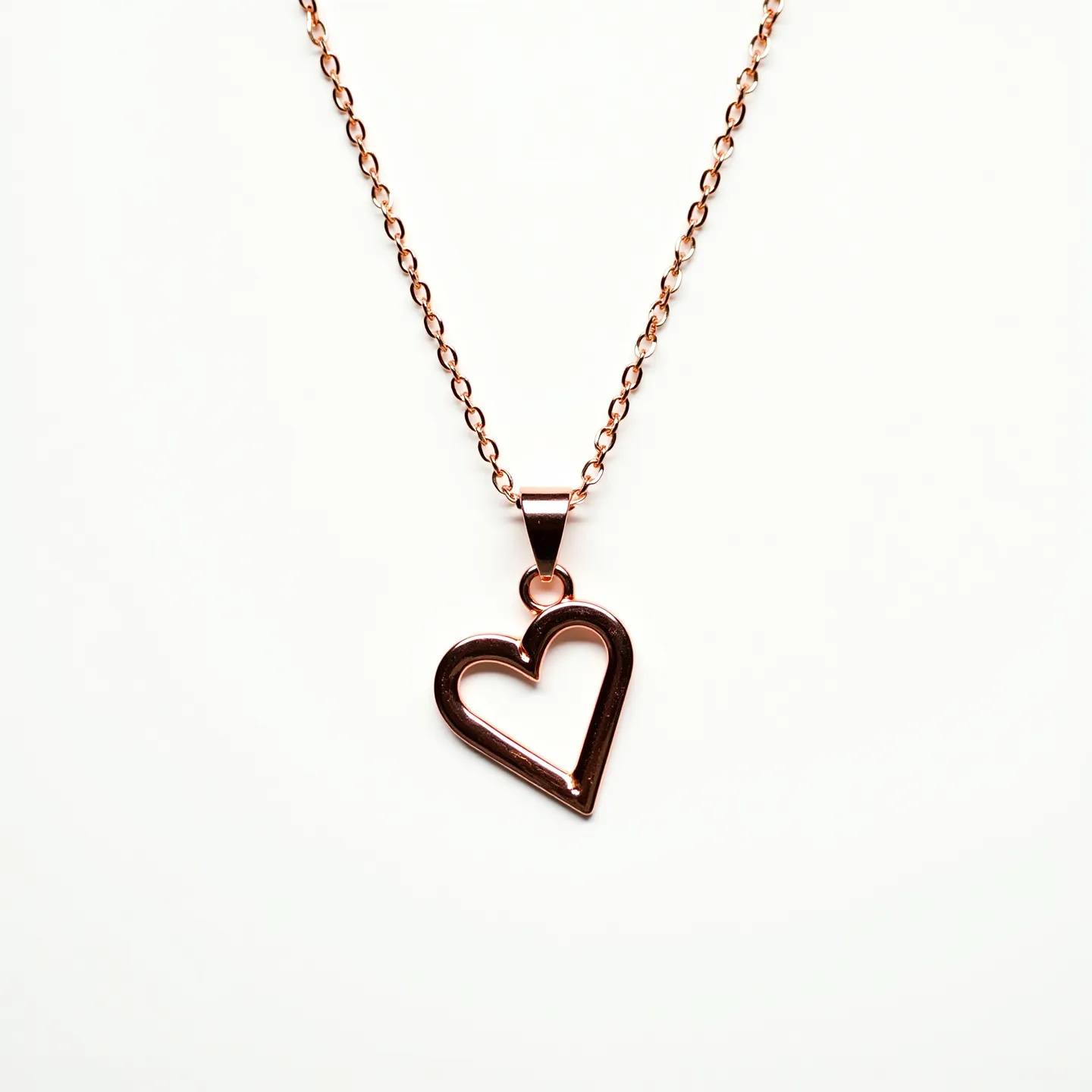 This heart necklace features a sleek, open heart-shaped pendant crafted from a polished metal, likely rose gold due to its warm hue. The pendant hangs elegantly from a simple, fine chain with a matching hue, linked via a smooth, tapered bail. The design is minimalist, emphasizing the metal's shine and smooth surface. The necklace is equipped with a basic clasp that allows for easy fastening and secure wear. Overall, the piece embodies elegance with its clean lines and understated design.