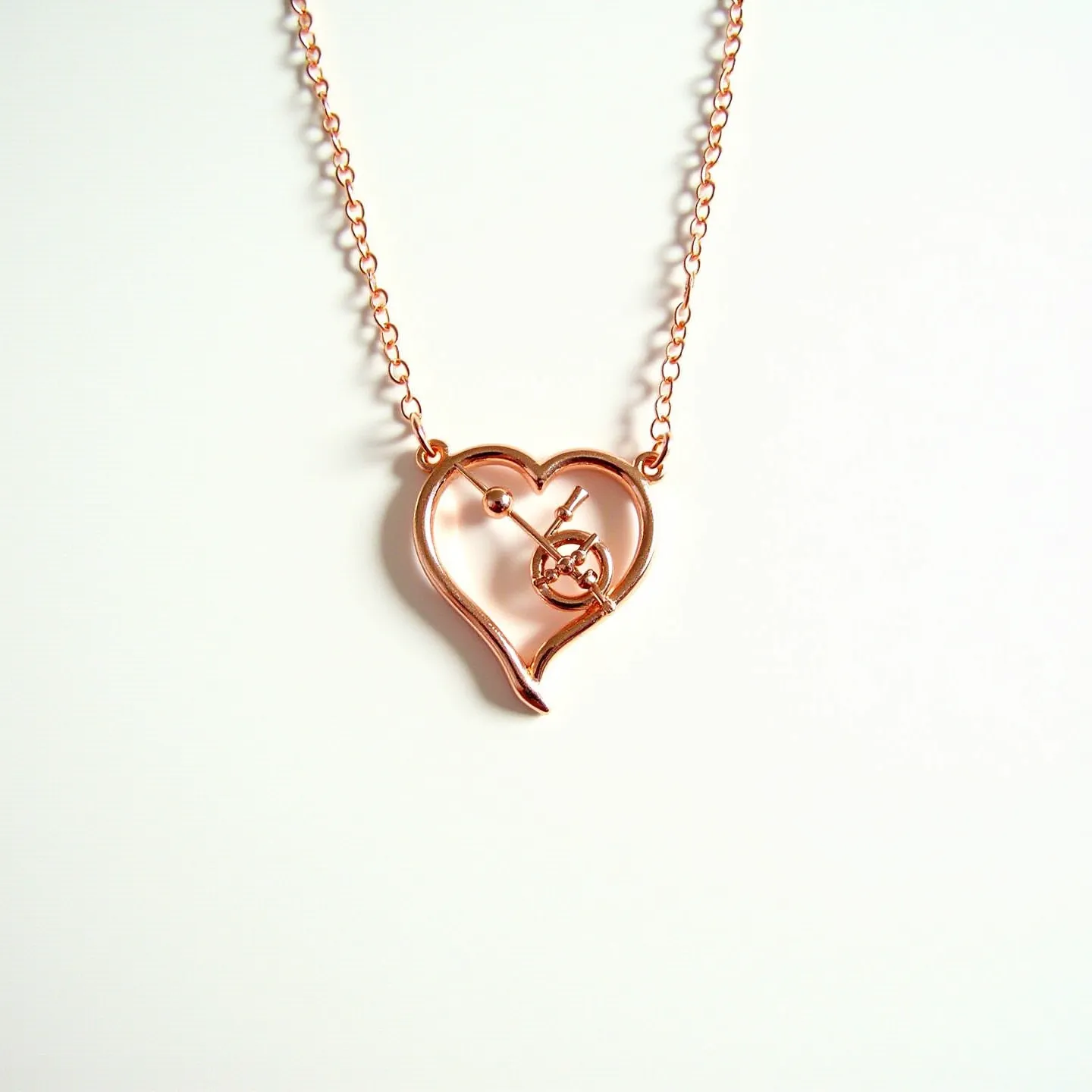 This heart necklace features a delicate, open-heart design crafted from a rose gold-toned metal, characterized by its smooth and polished finish. Its charm lies primarily in its minimalistic construction, with artistic elements incorporated into its framework, such as an abstract arrow intersecting the heart, evoking a sense of love struck imagery. The necklace includes a fine, matching rose gold chain that complements the pendant, ensuring a cohesive appearance. The chain appears to connect seamlessly to the pendant, highlighting the heart shape without visible disruption. An elegantly simple design, this necklace balances modern aesthetics with traditional motifs, making it a versatile accessory.