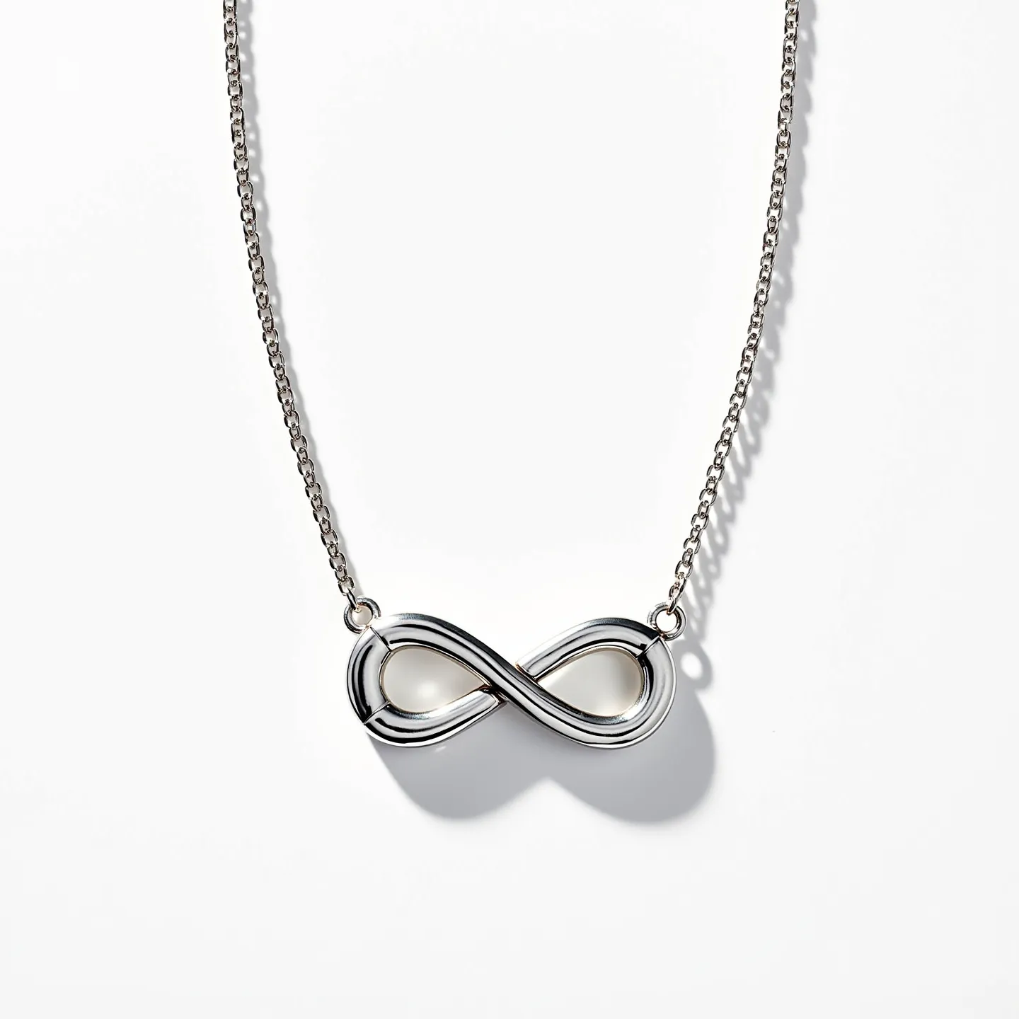 This infinity heart necklace features a sleek metal design, possibly crafted from sterling silver or white gold, forming a seamless infinity symbol intertwined with a heart shape. The pendant is elegantly polished, offering a reflective finish that enhances its sophisticated appearance. It is attached to a delicate chain that complements the pendant’s style, secured by small loops on either side of the infinity motif. The necklace closes with a lobster clasp, ensuring ease of wear and security.