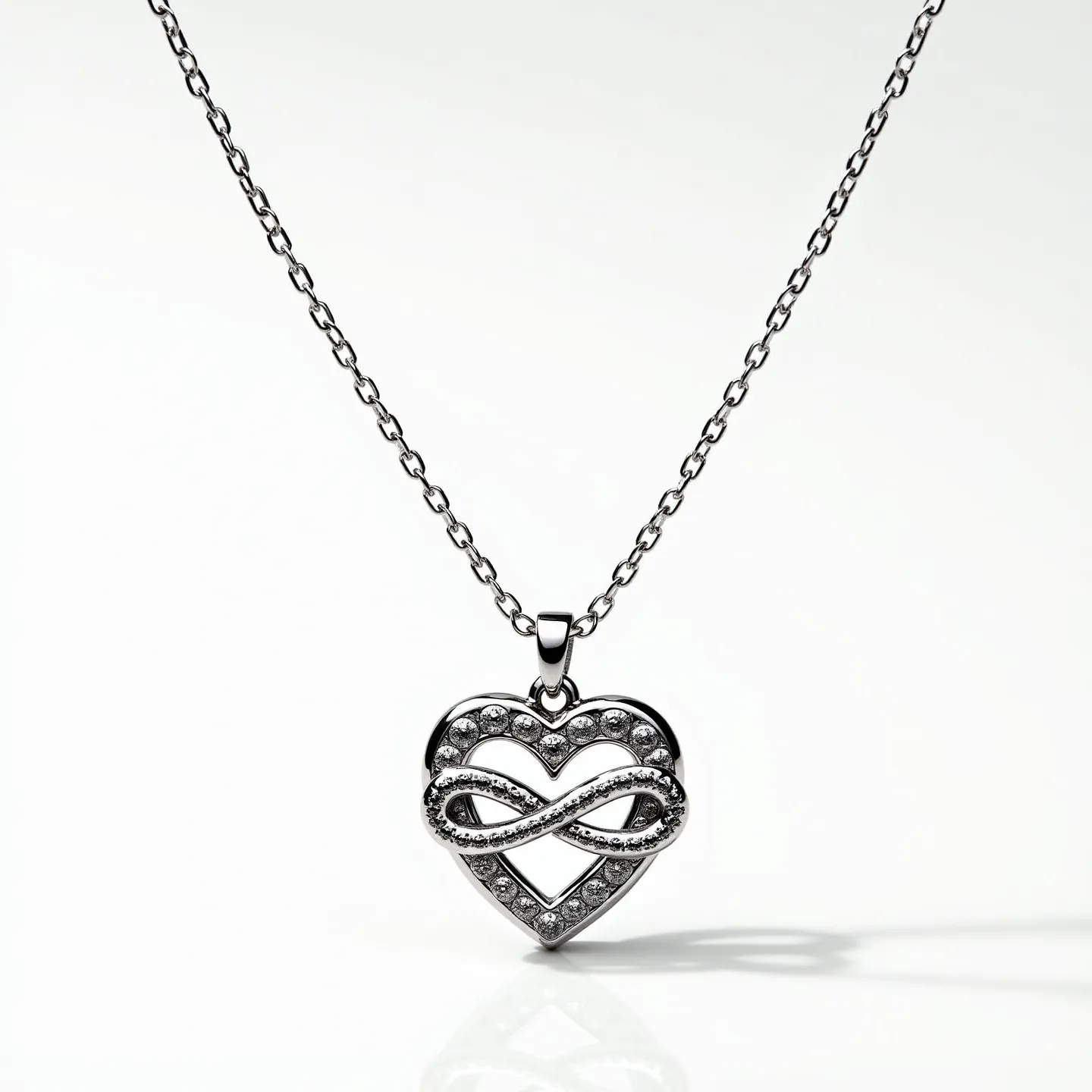 This infinity heart necklace features a heart-shaped pendant complemented by an intricately looped infinity symbol. The pendant is adorned with numerous small, round-cut clear stones, likely set in pavé style to enhance its sparkle. The metal appears to be a polished silver or white gold, adding a sleek, reflective quality to the necklace. The chain is composed of delicate links, providing a subtle yet sturdy support for the pendant. The attachment includes a standard jump ring and bail, allowing the pendant to hang gracefully from the chain.