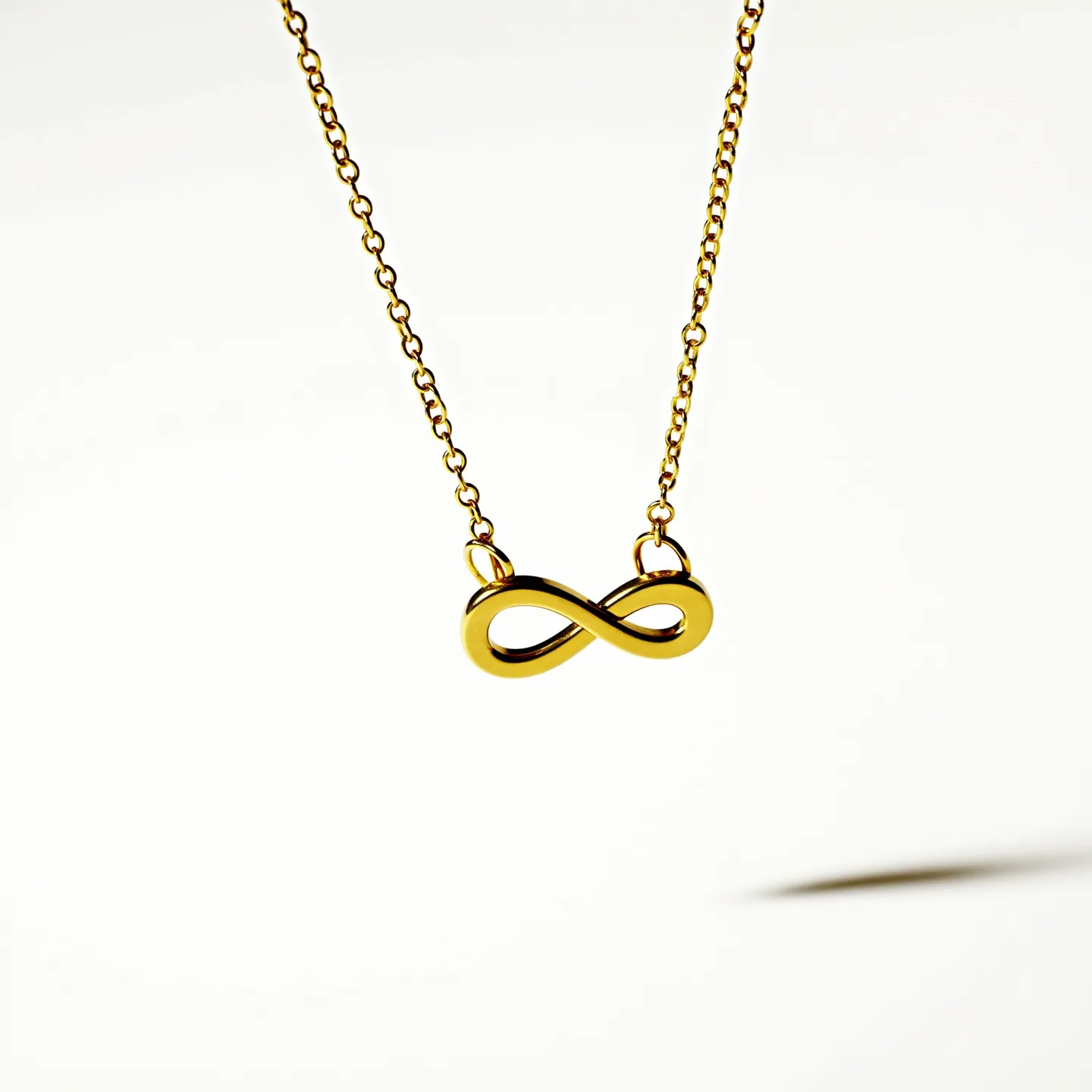 This infinity necklace features a sleek and polished infinity symbol crafted from gold. The symbol is elegantly suspended on a delicate gold chain, which highlights its minimalist and timeless design. The infinity pendant is attached securely to the chain with small, smooth loops. The chain is fine and closely linked, consistent with the overall streamlined aesthetic. The pendant lacks any additional embellishments, ensuring the focus remains on its gracefully curved form.