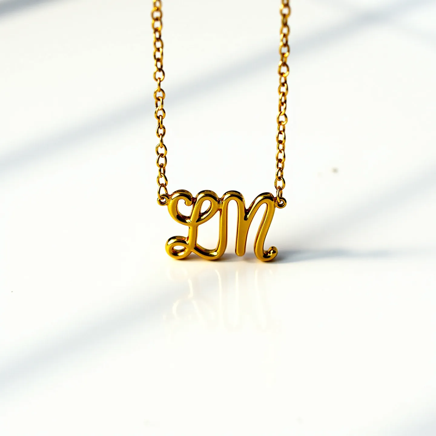 This initial necklace features the letters "LM" crafted in a script-style font, made from what appears to be gold or gold-plated metal, giving it a shiny and elegant look. The initials are integrated seamlessly into the necklace's design and are connected to a delicate golden chain. The chain complements the pendant, maintaining a consistent aesthetic throughout the piece. There are no visible gemstones set into the design, giving the necklace a simple yet sophisticated appearance. The necklace likely includes a standard clasp at the back to secure it around the neck, though it is not visible in the image.