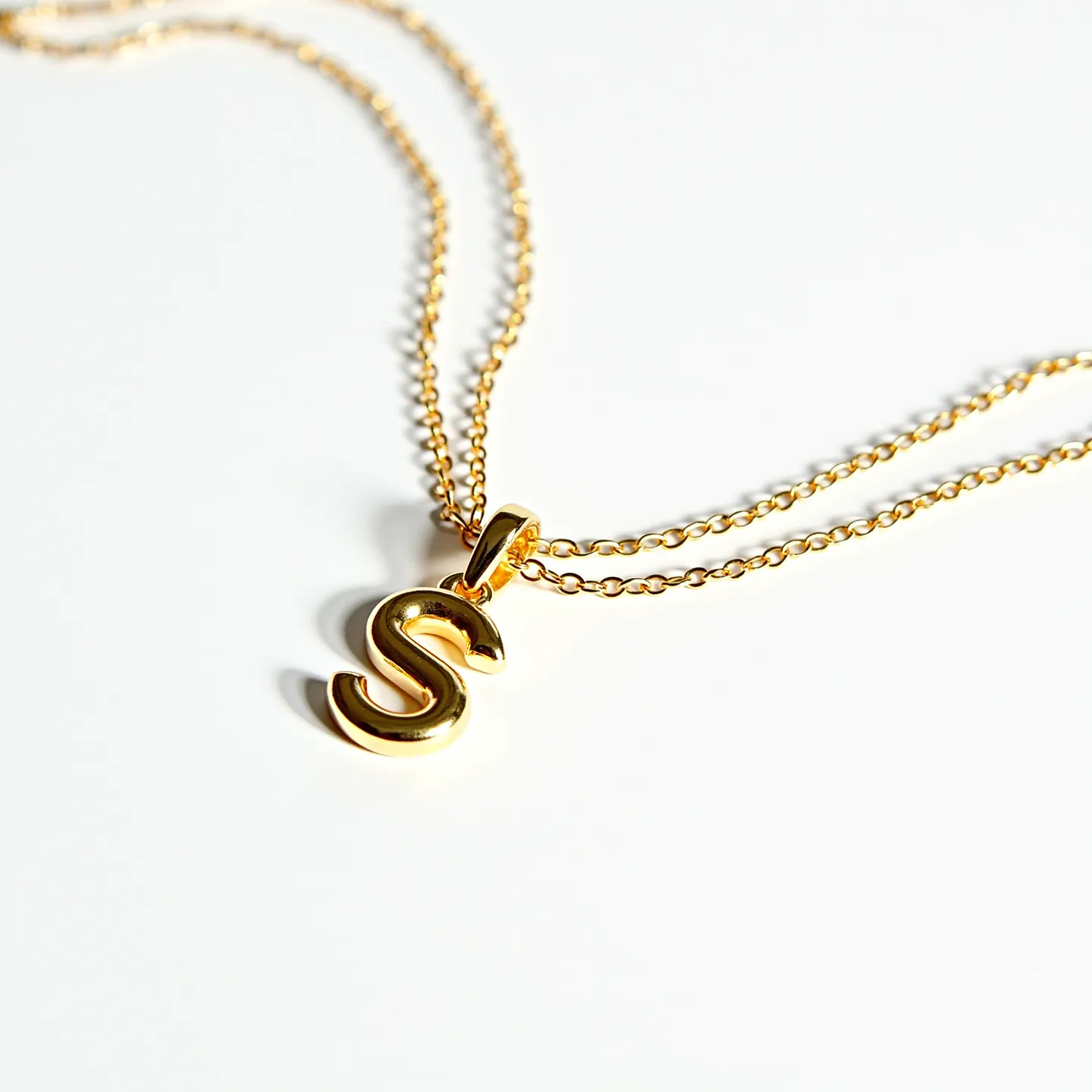 This initial necklace features a simple yet elegant design with a prominent "S" pendant. The piece is crafted from a lustrous gold-tone material, adding a touch of sophistication. The pendant is attached to a delicate gold chain that complements the overall look. The necklace is secured with a standard clasp, offering ease of use and security. The pendant showcases a smooth, polished finish, highlighting its minimalist and stylish appeal.