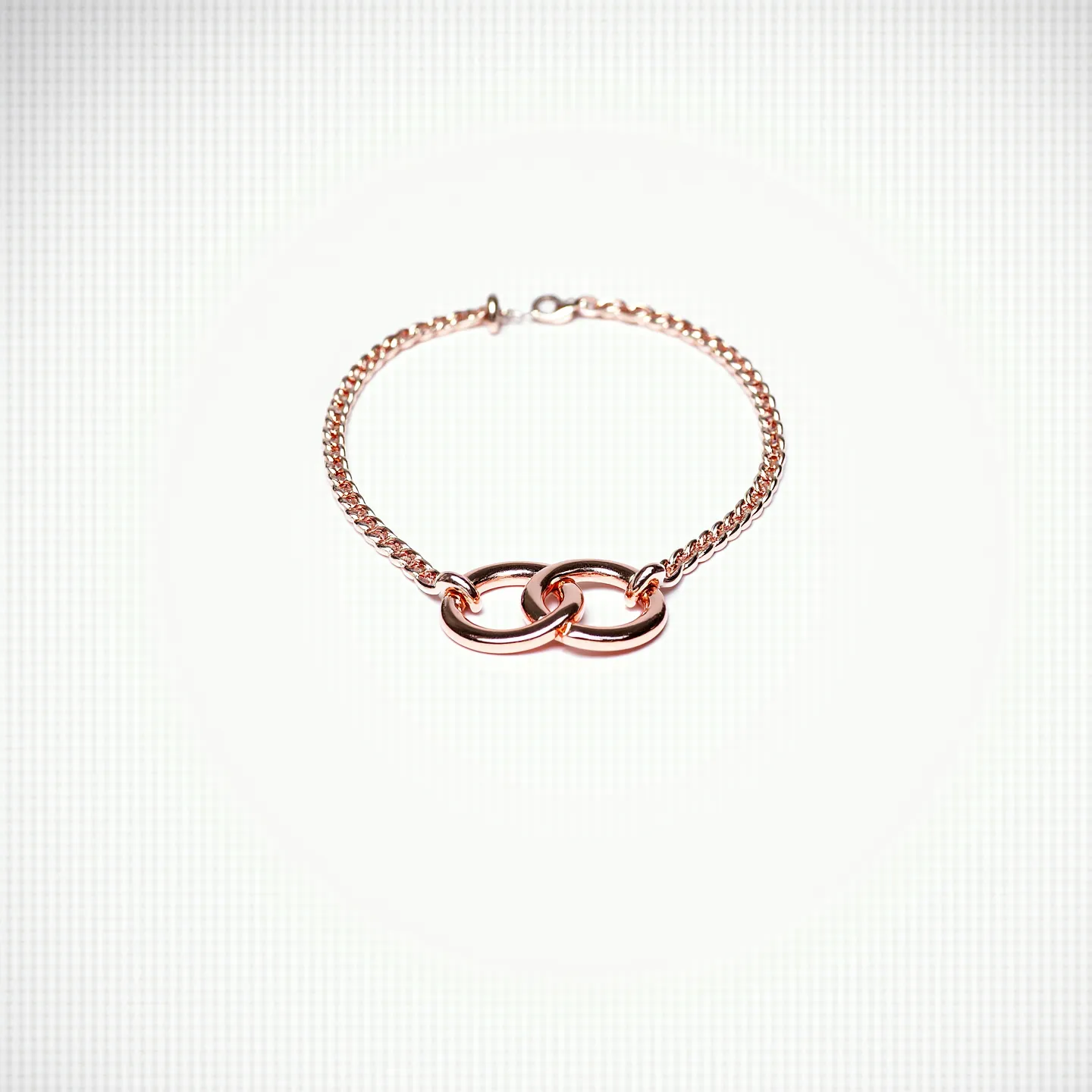 This interlocking circle necklace features two intertwined circles crafted from what appears to be a warm-toned metal, possibly rose gold. The circles are polished to a high shine, emphasizing their sleek, smooth design. They are attached to a delicate chain that matches the metal of the circles, providing a cohesive and elegant look. The necklace is secured with a simple clasp, ensuring it rests comfortably around the neck. The interlocking design symbolizes unity or connection, adding a layer of meaning to its aesthetic appeal.