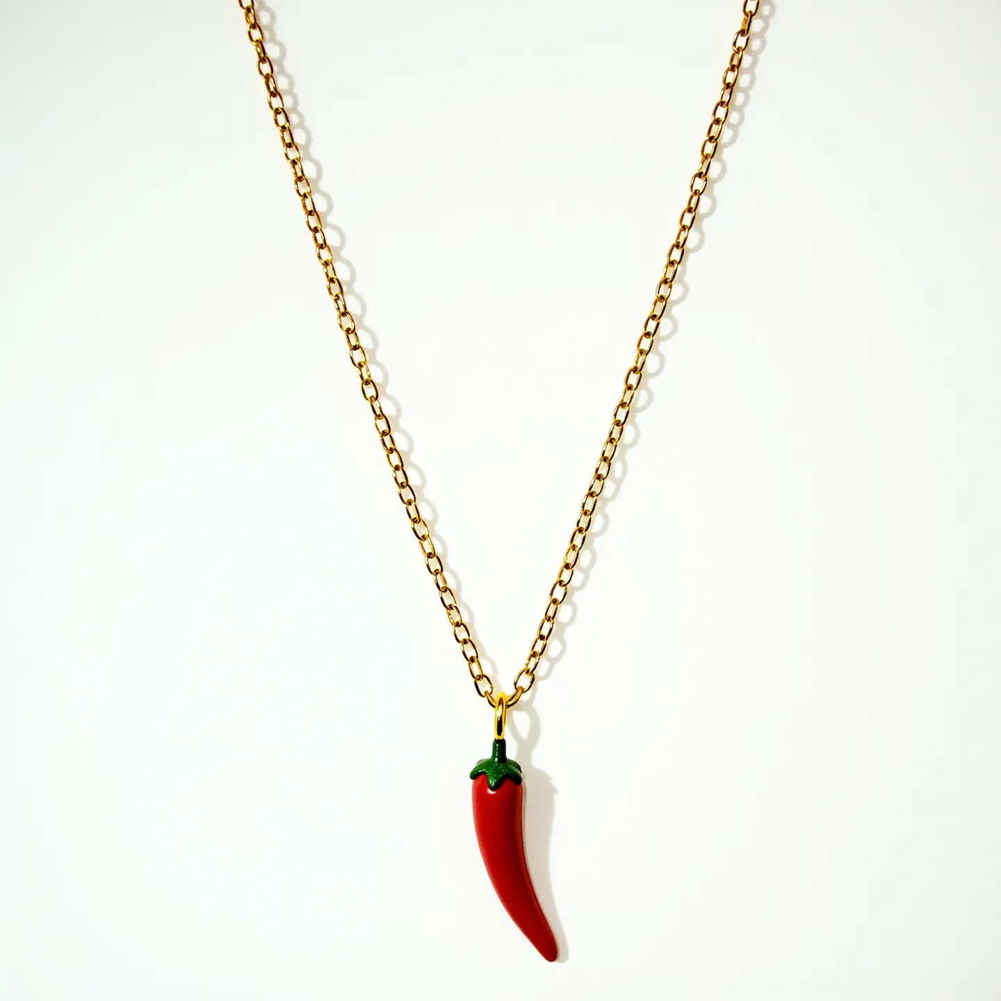 This Italian pepper necklace features a delicate chain crafted from what appears to be a gold-colored metal, creating an elegant and timeless appeal. At its center hangs a charm shaped like a red chili pepper, likely made from enamel or a similar glossy material that accurately captures the vivid color and shine of a real pepper. The pepper charm is detailed with a small green section at the top, representing the stem, and is attached to the chain with a simple metal loop or bail. The necklace is likely secured with a standard clasp, such as a lobster clasp or spring ring, ensuring easy wearability and secure attachment.