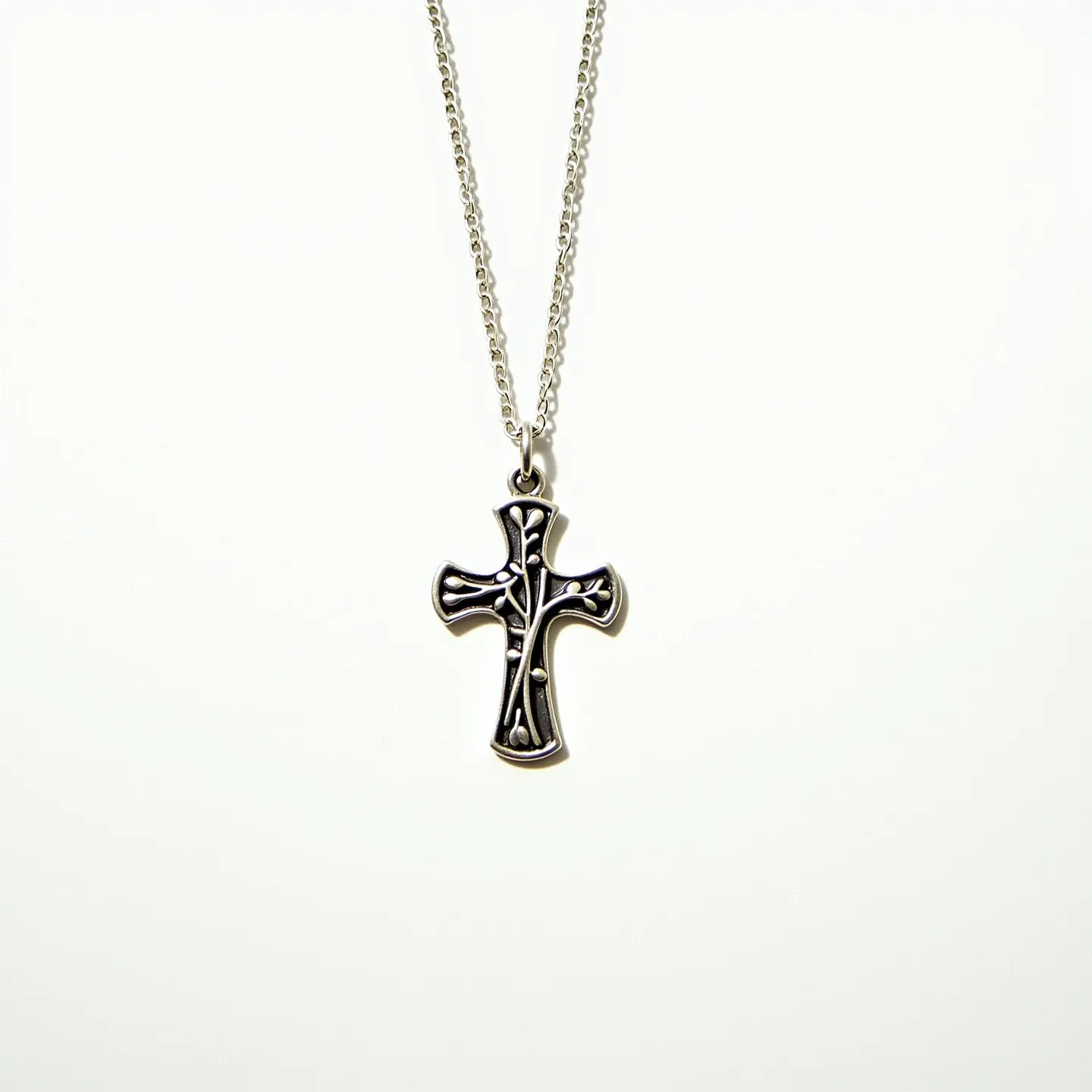 This kids cross necklace features a pendant crafted from what appears to be silver. The design incorporates a detailed branch-like texture across the surface, creating a visually striking appearance. The pendant hangs from a simple yet elegant chain, which is also likely made of the same silver material, contributing to a cohesive look. The necklace is equipped with a standard clasp, ensuring secure and easy fastening. The understated yet distinct design makes it suitable for children, combining both meaningful symbolism and stylish artistry.