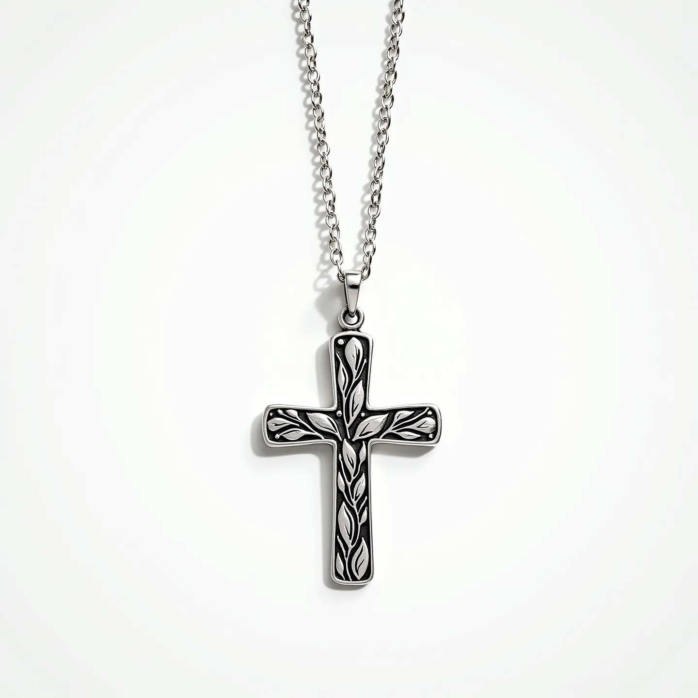 This kids cross necklace features a cross pendant with an intricate leaf design on a polished metal surface, likely made of stainless steel or silver-plated material. The cross is suspended from a chain with a simple cable link pattern, which complements the overall elegant yet youthful design. The pendant is securely attached to the chain with a jump ring, allowing for comfortable wear. The necklace's clasp appears to be a standard lobster clasp, ensuring easy fastening and removal. Overall, this piece combines aesthetic appeal with durable materials suitable for everyday wear.