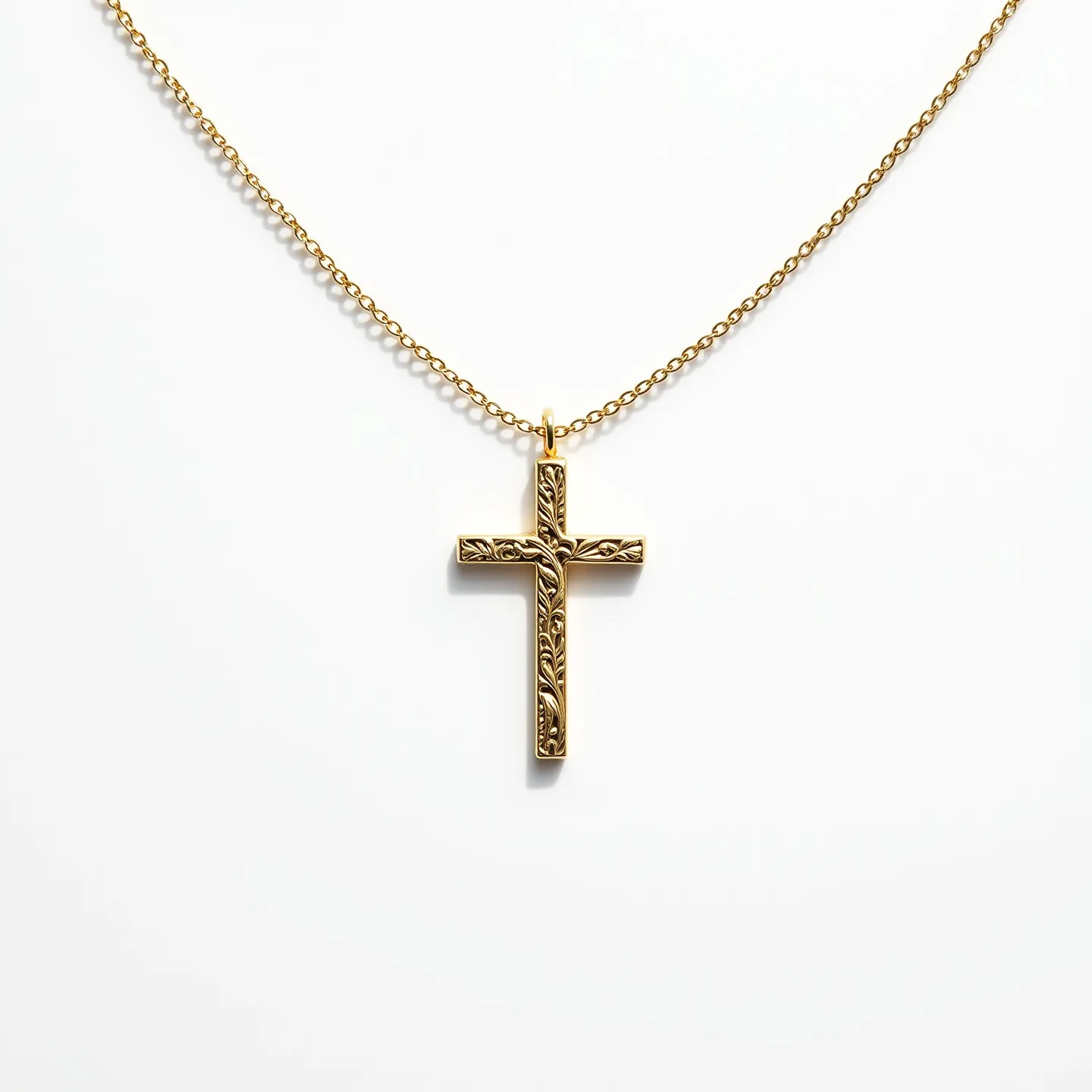 This kids cross necklace features a beautifully crafted cross pendant made of gold, exhibiting intricate engraved patterns that resemble leaves and vines, adding a touch of elegance and sophistication. The pendant hangs from a fine gold chain, which complements the design seamlessly. The cross is suspended using a simple, unobtrusive loop at the top, effectively integrating the design with the chain while ensuring secure attachment. The chain is equipped with a standard clasp closure, allowing for easy wear and removal, making it suitable for young users. The overall design showcases a classic and timeless appeal, combining aesthetic craftsmanship with functionality.