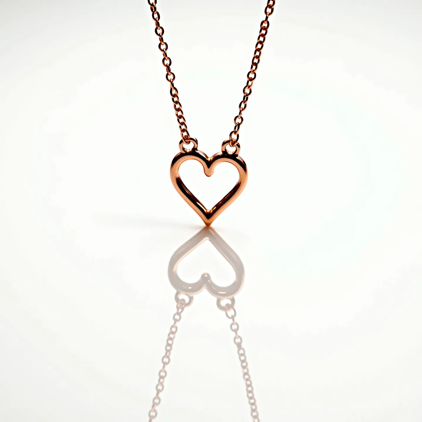 This kids gold necklace features a delicate heart pendant crafted from polished rose gold, giving it a warm, inviting hue. The pendant is symmetrically shaped and elegantly simple, without any additional embellishments or gemstones. The necklace chain consists of small, interlinked round links that provide a subtle sparkle and fine texture, contributing to the overall dainty appearance of the piece. A standard spring ring clasp, which is secure and easy to handle, completes the necklace, making it suitable for a child's use. The design combines charm with practicality, making it both an attractive and wearable piece of jewelry for a young individual.