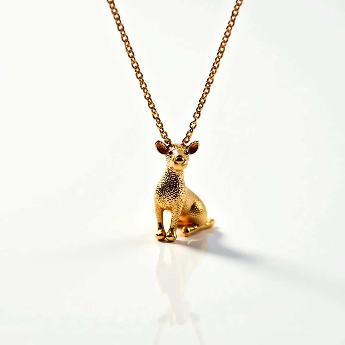 This kids gold necklace features a charming pendant crafted in the shape of a sitting dog. Made from gold-toned metal, the pendant exhibits a finely textured surface that adds a subtle dimension to its whimsical design. The necklace consists of a delicate yet sturdy chain, and it seamlessly attaches to the pendant, enhancing its playful aesthetic. The necklace is secured with a standard spring ring clasp, ensuring easy wearability and a secure fit for such an adorable accessory.