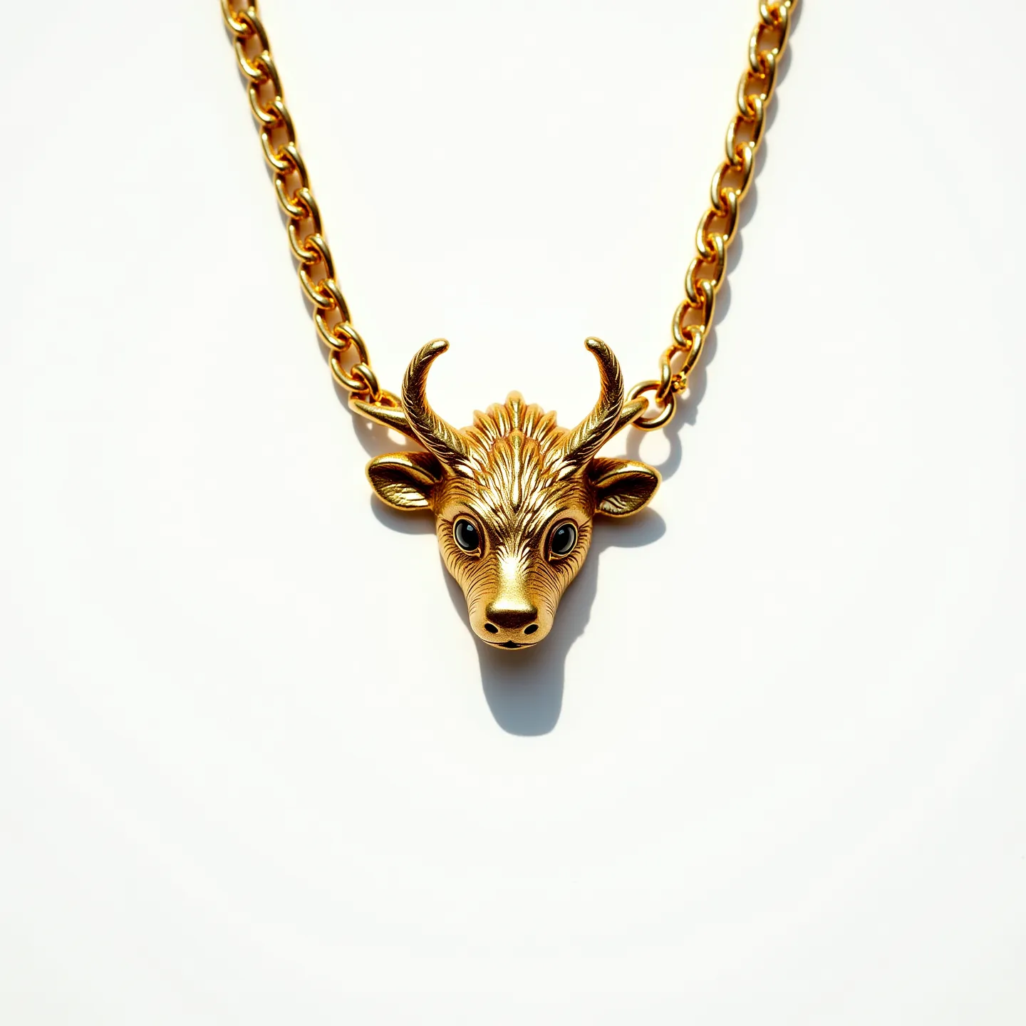 This kids gold necklace features a charming design with a chain made from gold links, exhibiting a bright and polished finish. At its center, the necklace displays a pendant shaped like a bull's head, crafted from gold, showcasing intricate detailing on the face and horns. The eyes of the bull appear to be set with small, round stones that add a touch of elegance. The necklace is equipped with a secure clasp, ensuring it stays fastened comfortably around the neck. This piece blends playful design with sophistication, making it a unique accessory.