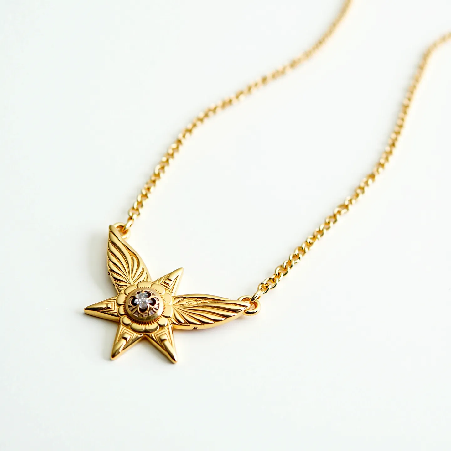 This kids gold necklace features a delicate chain paired with a striking star-shaped pendant adorned with finely detailed wings. At the center of the star is a small, round gem that appears to be a brilliant cut, securely set within a simple bezel setting. The gold finish gives the necklace a warm and classic appeal, suitable for young wearers. The chain is likely created from gold-plated or solid gold links, adding durability and shine. A standard spring ring clasp or a similar attachment would typically secure this necklace, ensuring it remains safely fastened around the neck.