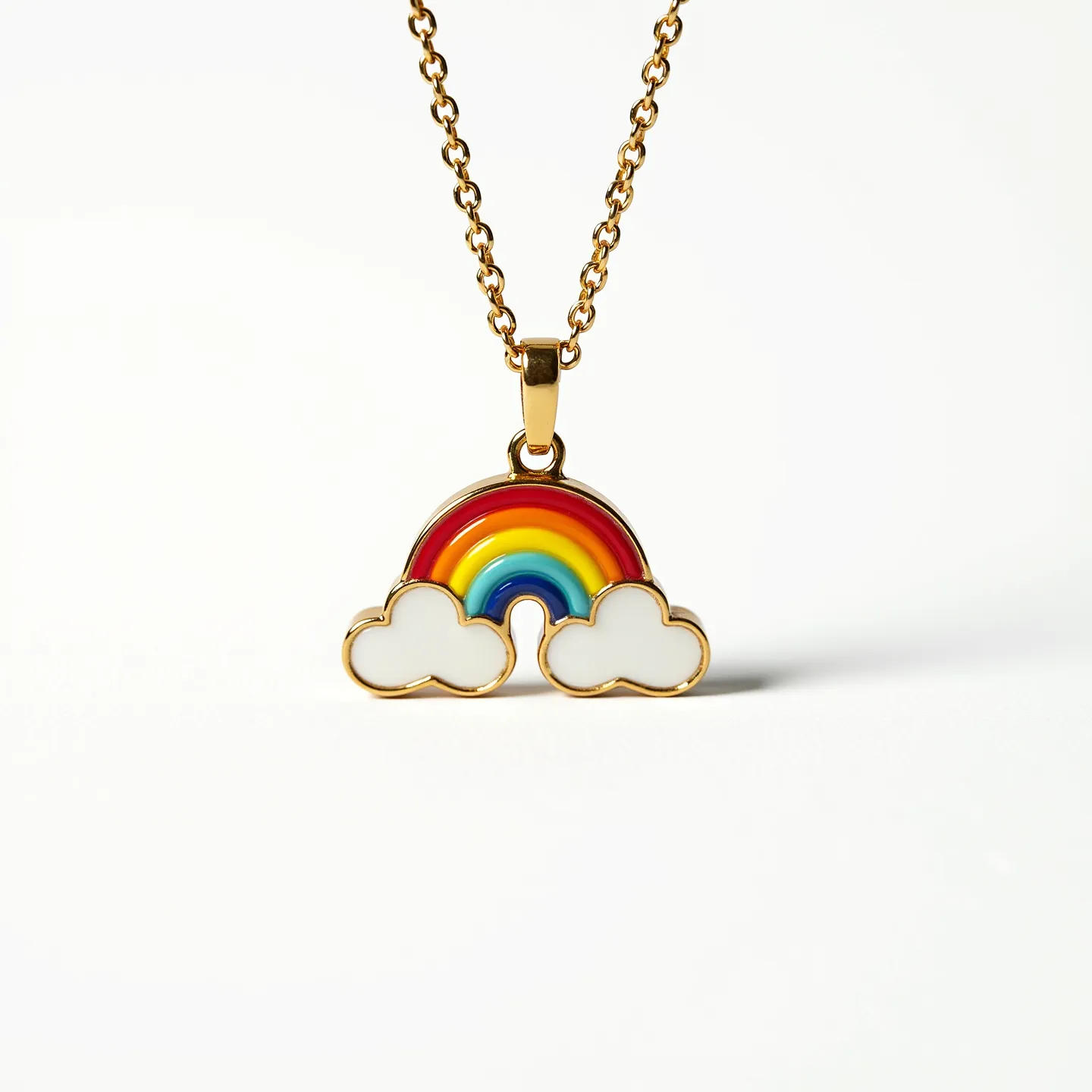 This kids' gold necklace features a charming pendant shaped like a rainbow flanked by two clouds. The pendant is crafted with vibrant enamel in rainbow colors—red, orange, yellow, green, blue, and indigo—highlighting the arc, while the clouds are depicted in white enamel, providing a playful contrast. The gold setting offers a sleek border defining the shapes clearly. The chain is composed of interlocking gold links, combining durability with an elegant appearance. The pendant is secured to the chain with a small, integrated gold bale that allows for easy movement and flexibility.