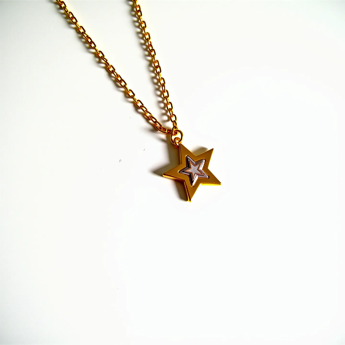 This kids gold necklace features a charming star-shaped pendant crafted from a shiny gold material. The star has a smaller, inset outline that adds dimension to the piece. The chain itself is composed of simple, small links that enhance the necklace’s delicate appeal, suitable for a child. The pendant is affixed to the chain with a small, round attachment that allows for gentle movement. The closure of the necklace is not visible, but it likely employs a standard clasp typical of children's jewelry for easy fastening and removal.