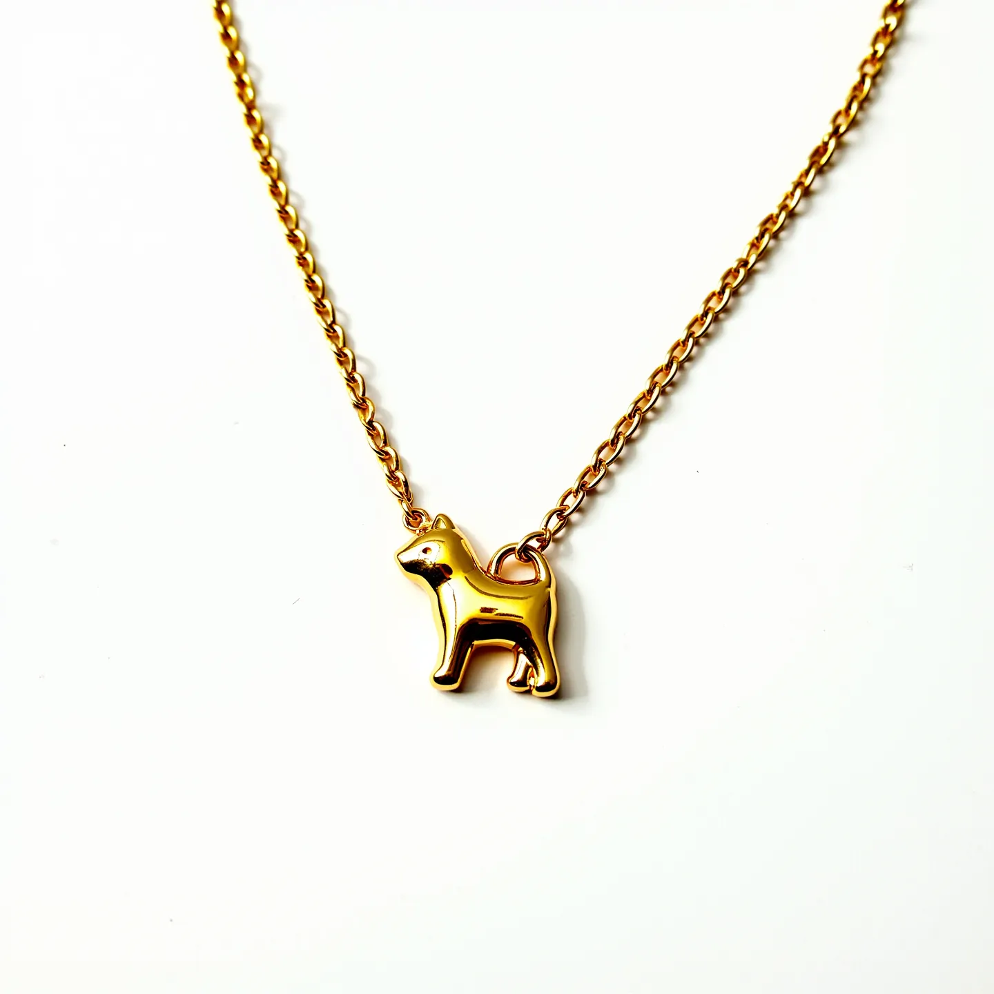 This kids gold necklace features a delicate chain crafted from polished gold links, creating a subtle yet elegant design suitable for children. The centerpiece of the necklace is a charming gold pendant shaped like a small dog, which adds a playful and personalized touch. The pendant is securely attached to the chain with a robust loop, ensuring durability. The chain likely includes a standard clasp for easy fastening and removal, though it is not visible in this view. The overall design is simple yet sophisticated, making it an appealing accessory for young wearers.