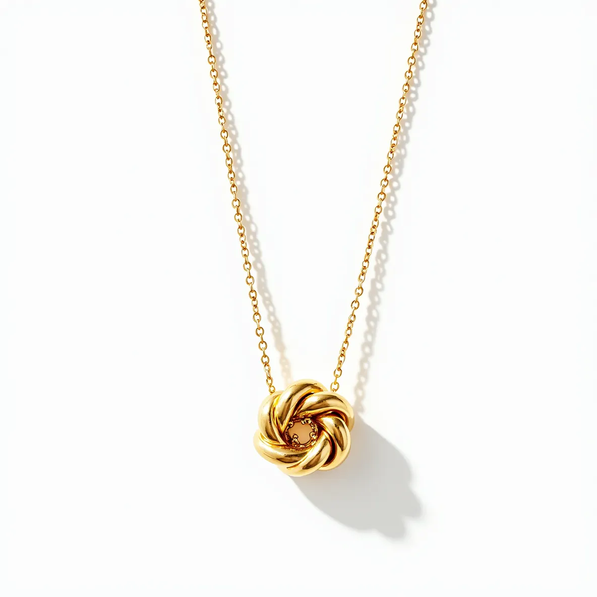 This knot necklace features an elegant design with interwoven loops crafted from polished gold-tone metal, giving it a sleek and sophisticated appearance. The focal point of the necklace is the knot pendant, which is smooth and reflective, showcasing expert craftsmanship. The necklace includes a delicate chain that complements the pendant, likely made of the same material to maintain a cohesive look. The clasp is a standard lobster clasp, ensuring a secure and easy-to-use fastening mechanism. This piece combines simplicity and elegance, making it versatile for various occasions.