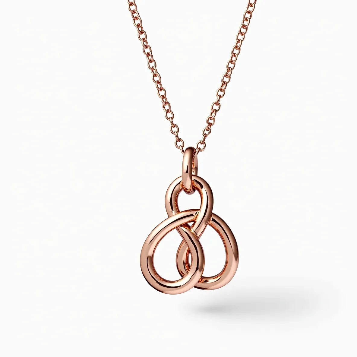 This knot necklace features an elegant design crafted from rose gold, with intricate interlocking loops creating a stylish knot as its central feature. The pendant hangs gracefully from a fine rose gold chain, showcasing a sleek and polished finish that enhances its luxurious appeal. The necklace is equipped with a secure clasp for easy and reliable fastening. There are no stones or gems incorporated into this design, allowing the metallic craftsmanship to be the focal point of this piece.