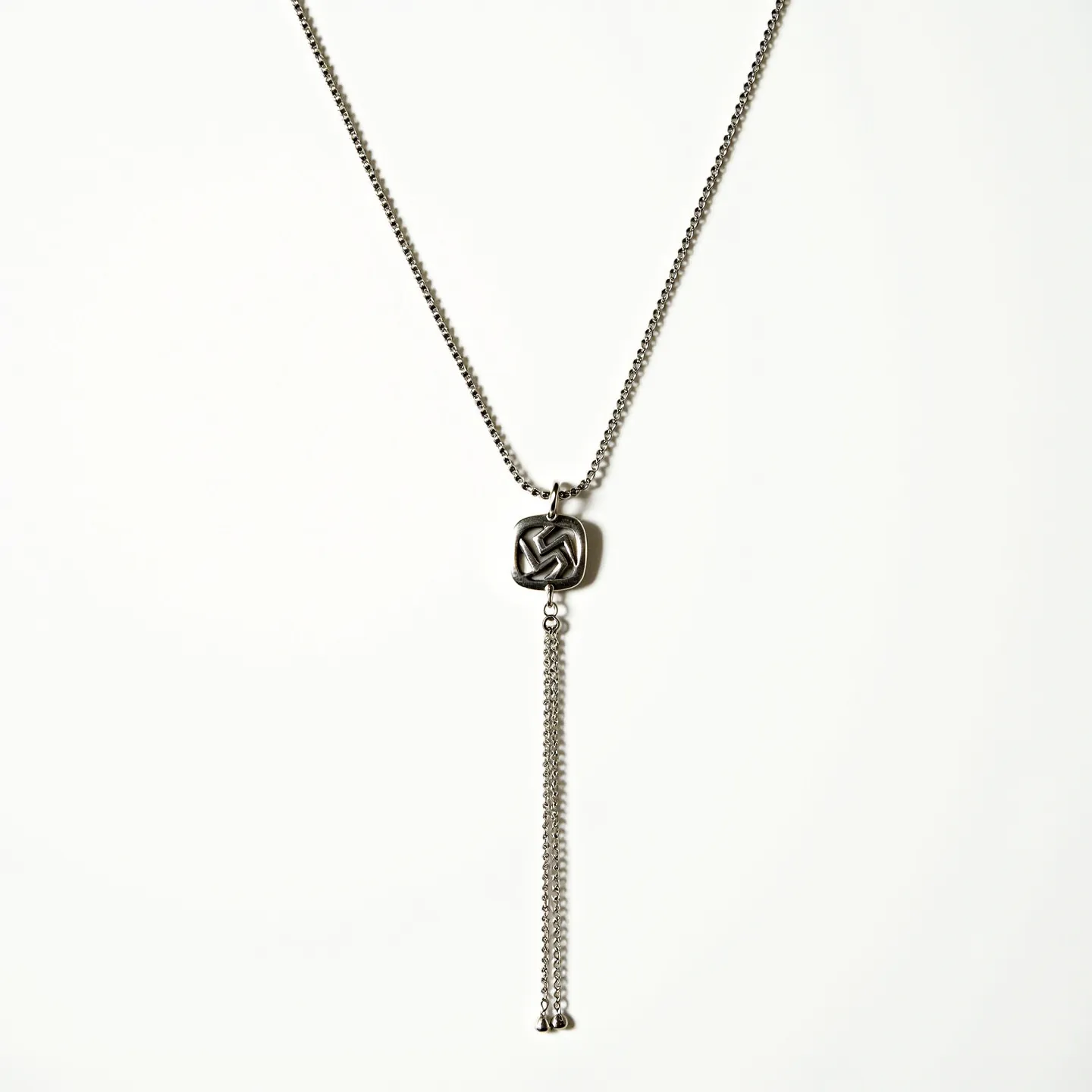 This lariat necklace features a sleek, metallic chain with a distinctive knot design at its apex, serving as a focal point. The chain appears to be made of a polished stainless steel or similar metal, providing a contemporary and durable finish. The knot design is intricately crafted, showcasing a looping pattern that adds visual interest without the inclusion of gemstones. Below the knot, multiple strands of the same chain material dangle elegantly, enhancing the necklace's lariat style. The necklace does not utilize a traditional clasp, instead relying on its open-ended design to adjust the fit dynamically, emphasizing its modern and minimalist aesthetic.