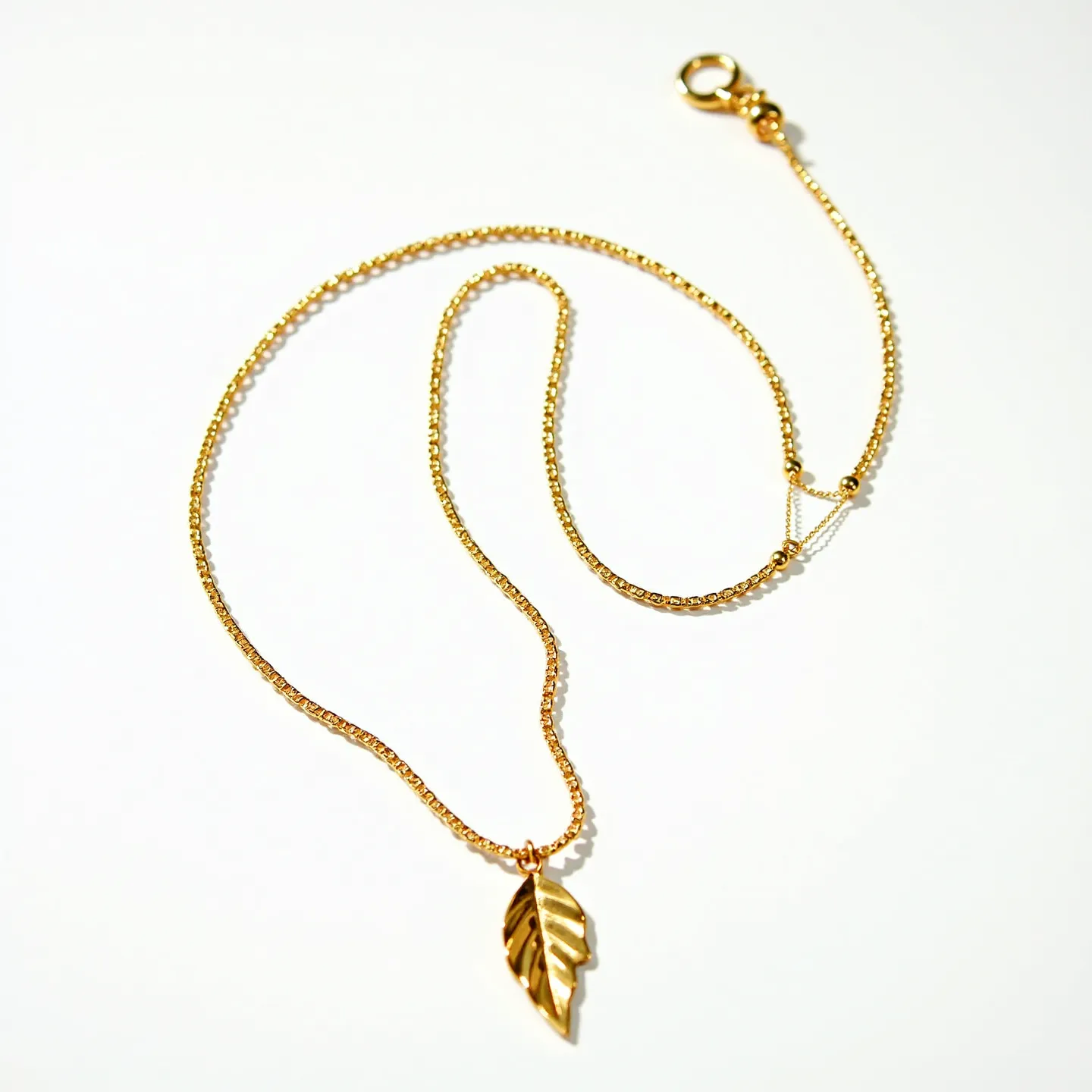 This lariat necklace features a delicate gold chain adorned with a polished leaf pendant, adding a touch of natural elegance to the design. The chain consists of fine links that contribute to its refined appearance. The pendant is simple yet striking, enhancing the overall aesthetic of the necklace. It is attached to the chain without visible prongs or bezels, suggesting a minimalist setting. The necklace secures with a lobster clasp, ensuring easy wear and security while maintaining a seamless look.