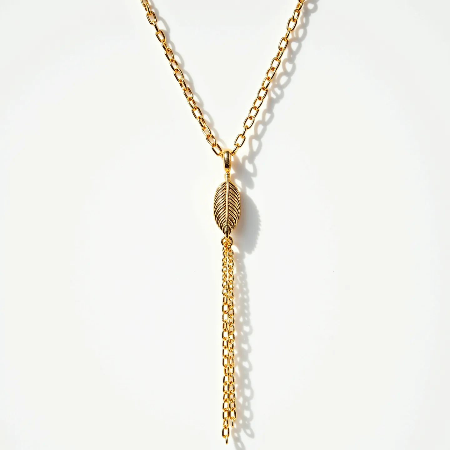 This lariat necklace features a gold-tone chain with a distinctive leaf-shaped element at its center. The leaf pendant connects to multiple chain tassels, adding elegance and movement to the design. The necklace utilizes the lariat style's versatility, allowing for adjustable length and styling options. The polished finish of the metal gives it a luminous quality, emphasizing its refined aesthetic.