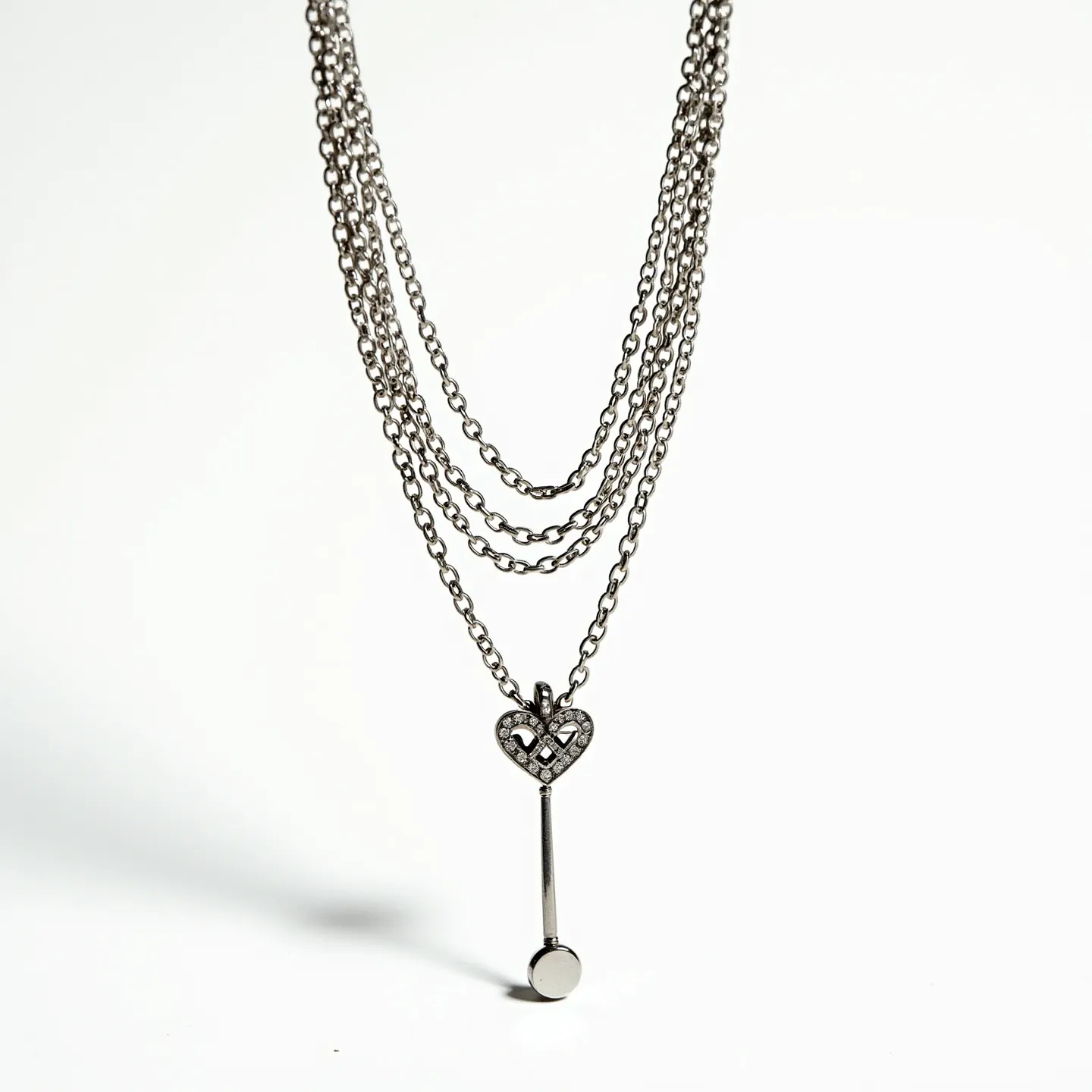 This layered necklace features multiple strands of fine, metallic chains, creating a cascading effect. It showcases a pendant at the center, consisting of a heart-shaped element adorned with small, round, clear gemstones, likely set in a prong setting that enhances their sparkle. Below the heart motif, a vertical, polished metal rod extends, terminating in a small circular disc. The clasp and attachment details are not visible, but the overall design suggests a modern and stylish aesthetic. The necklace's metallic elements have a lustrous finish, adding to its elegant appearance.