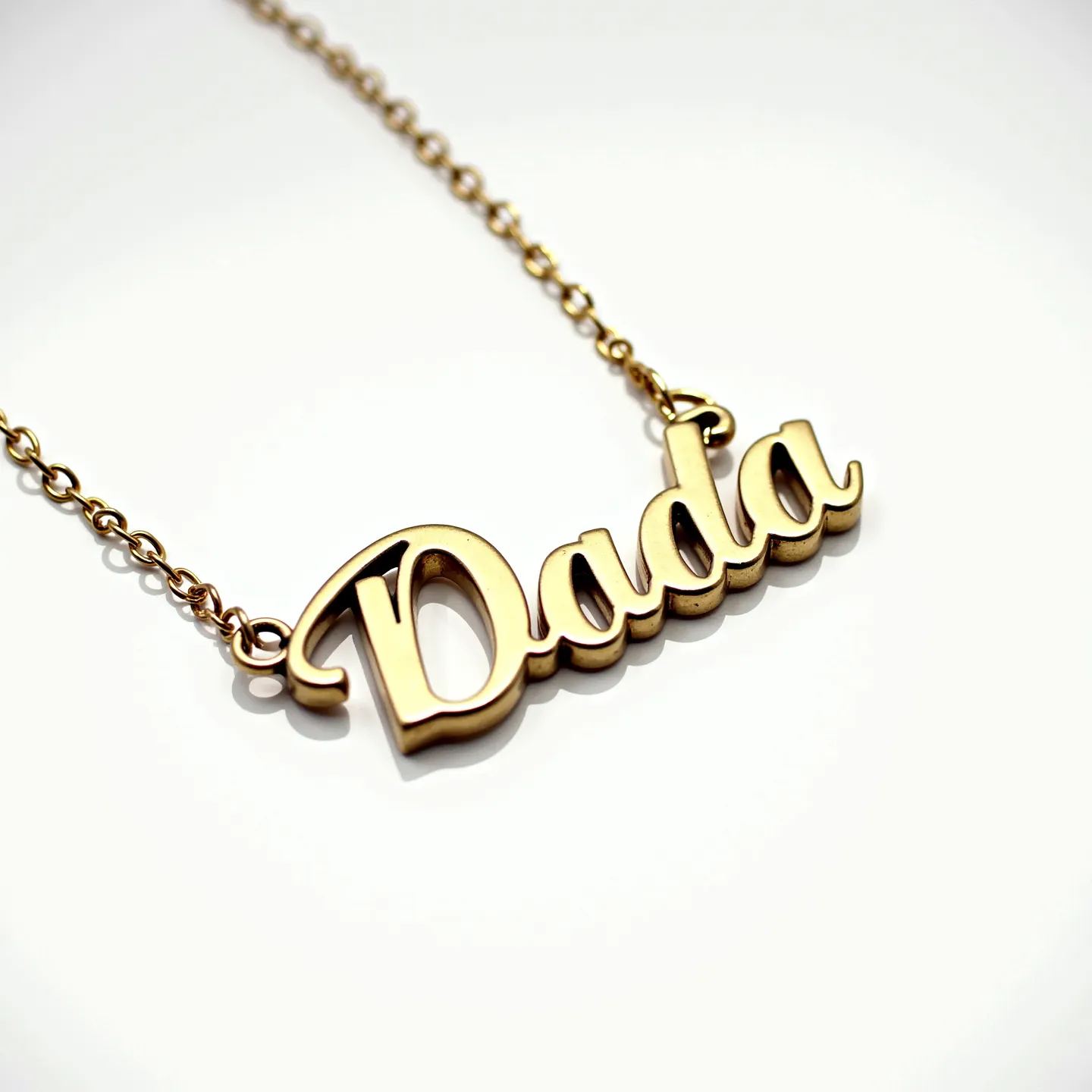 This letter necklace features the word "Dada" crafted in a bold, scripted font. The material appears to be a polished metal, likely gold or gold-plated, giving it a shiny, luxurious finish. The letters are smoothly integrated and suspended from a delicate chain that complements the pendant's color and texture. The necklace includes loops on either end of the word, connecting seamlessly to the chain, although details about the clasp cannot be discerned from the image. The overall design combines elegance and simplicity, making it a stylish accessory.