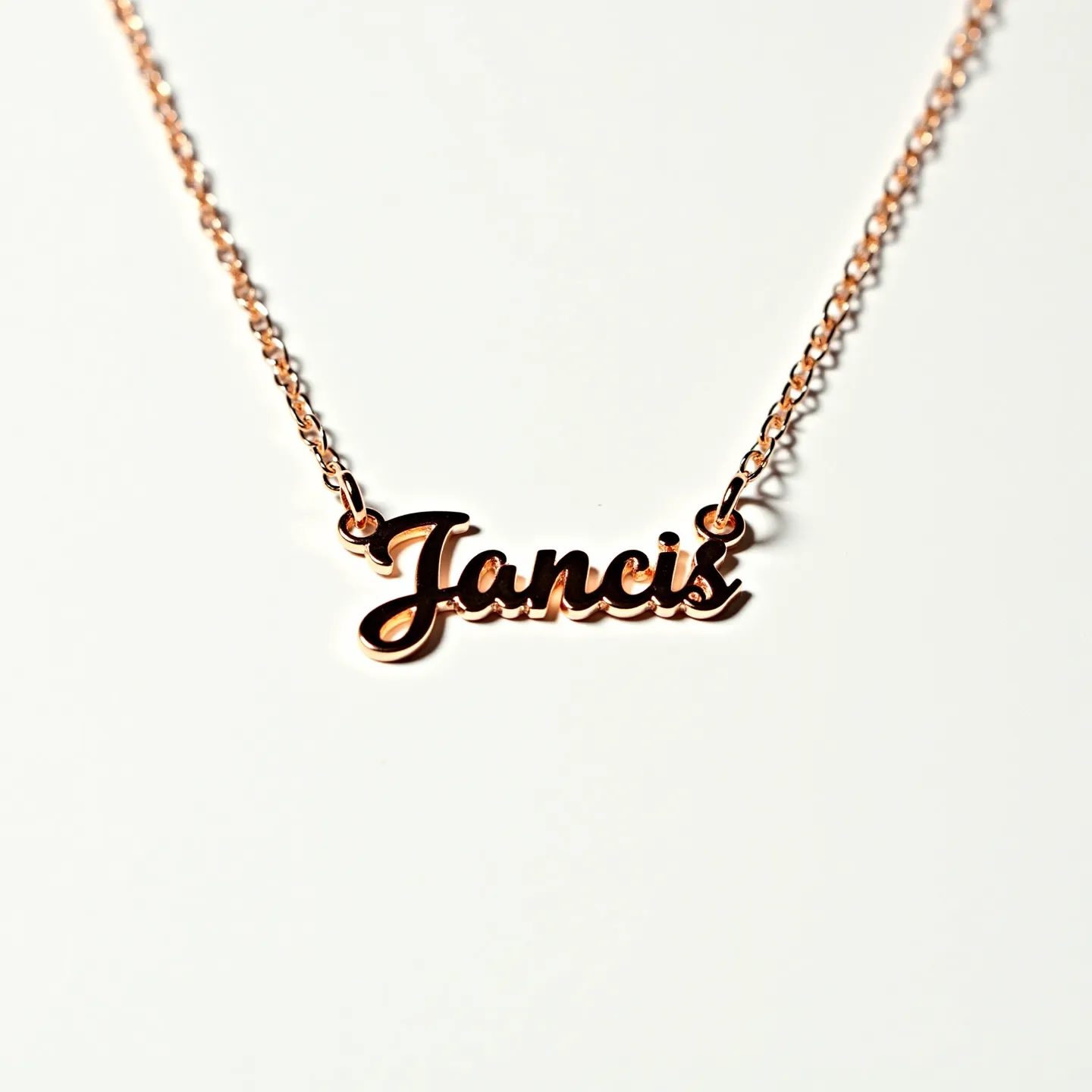 This letter necklace features the name "Jancis," crafted in a cursive script that exhibits a delicate and elegant flair. The material appears to be a shiny metal with a warm, gold-toned finish, suggesting it might be rose gold or a similar alloy. The letters are smoothly cut and polished, giving them a sleek look. They are connected to a fine chain with a matching metal hue, which appears to be linked with small, uniform oval links. The chain attaches to the lettering via rings on either side, securing the letters in place with a simplistic elegance. The design focuses on the refined aesthetic of the name as it hangs elegantly centered on the collarbone.