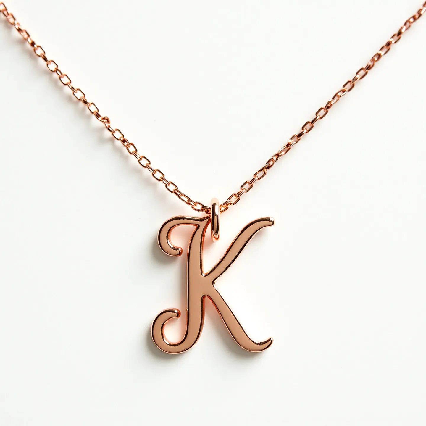 This letter necklace features a finely polished letter "K" in a lustrous rose gold color, suggesting it may be crafted from rose gold or rose gold-plated metal. It is elegantly suspended from a delicate chain, also matching the rose gold hue, which provides a cohesive and classy look. The letter is attached to the chain with a small loop that is both simple and secure, ensuring that the pendant remains the central focus.