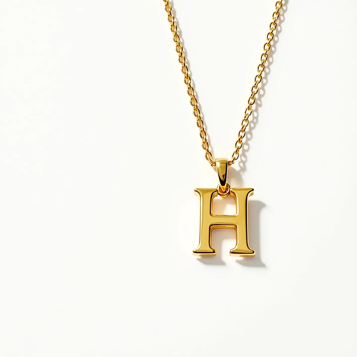 This letter necklace features a bold, gold-plated letter "H" pendant, suspended from a matching gold chain. The pendant has a polished finish, giving it a sleek and shiny appearance. The chain is composed of interlocking links, providing a classic look that complements the elegant design of the letter. It is attached to the pendant with a simple bail, enhancing the smooth transition between the chain and the pendant. The necklace is secured with a small, discreet clasp that ensures easy wearability.