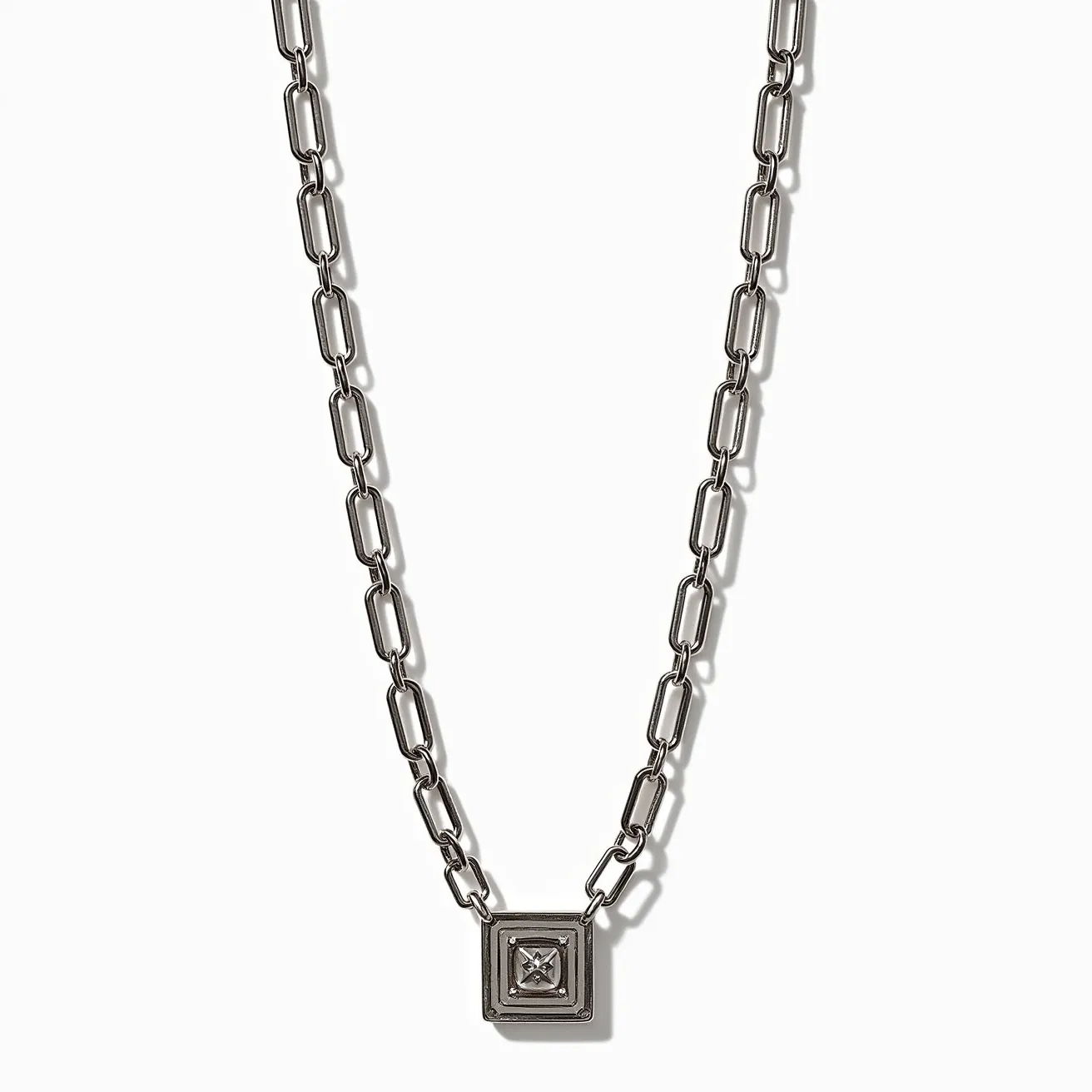 This link necklace features a sleek, industrial design composed of rectangular metal chain links in a polished silver tone. Each link is smoothly connected, offering a seamless and sturdy appearance. At the center of the necklace, there is a square pendant that houses a gemstone with a princess cut, set securely within a bezel setting. The stone is likely a clear gem, adding a subtle sparkle to the piece. The clasp appears to be a simple and functional lobster clasp, ensuring easy and secure attachment.