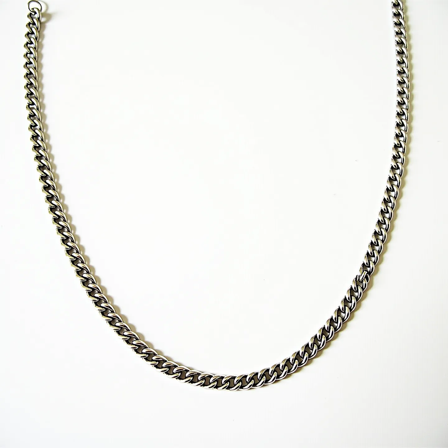 This link necklace features a classic curb chain design made of metal with a polished finish, possibly stainless steel or sterling silver. The interlocking links create a sleek and uniform appearance, contributing to its understated elegance. Each link is smoothly curved, allowing for fluid movement and a comfortable fit. The necklace is secured with a lobster clasp, offering a simple yet effective means of attachment. Its minimalist design makes it versatile for various styles and occasions.