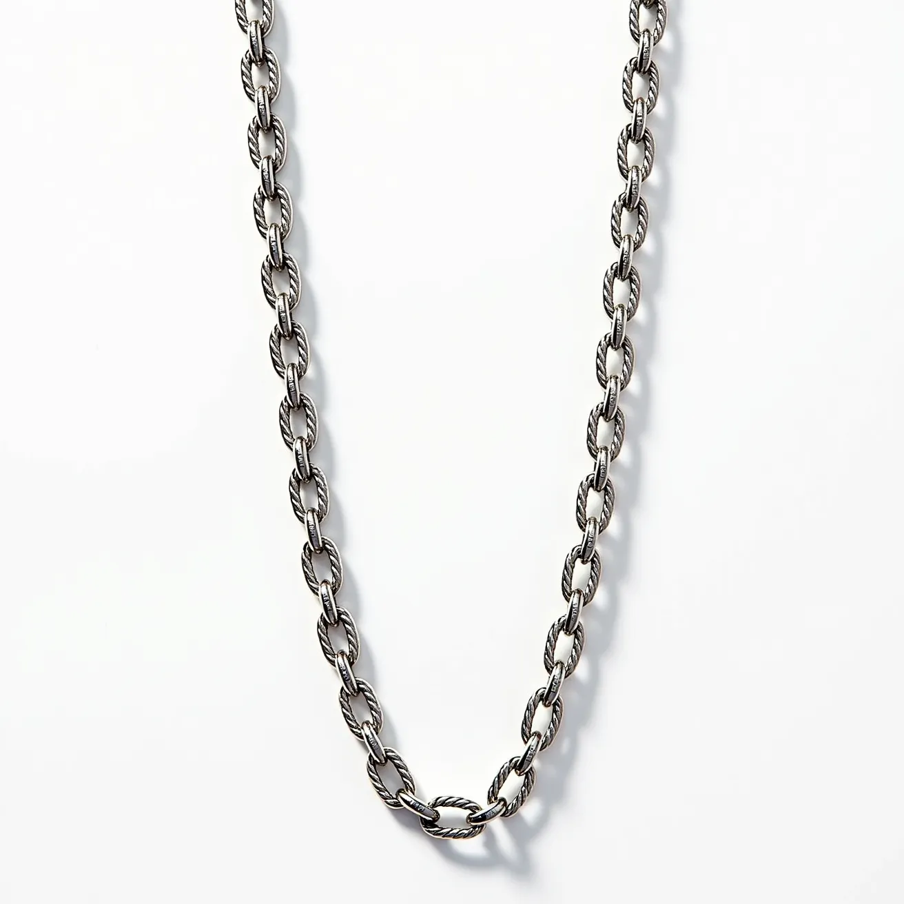 This link necklace features interlocking oval links crafted from a dark silver-toned metal, giving it a sleek and sophisticated appearance. Each link displays a rope-like texture, which adds a touch of elegance and dimension to the overall design. The necklace is securely fastened with a lobster clasp, ensuring ease of wear and durability. No gemstones are present, which highlights the intricate detailing of the metal itself. The overall style combines classic design with modern elements, making it versatile for a variety of occasions.