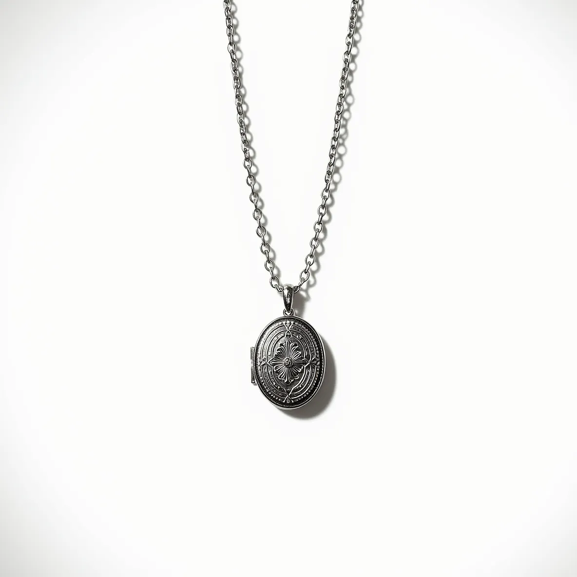 This locket necklace features an intricately designed oval pendant, crafted from what appears to be silver or a similarly toned metal, showcasing detailed engravings that suggest a vintage or antique style. The locket is attached to a cable chain, creating a cohesive look with its uniform links. There are no visible gems or stones set into the pendant, emphasizing the ornamental engraving as the primary decorative element. The clasp is a standard spring ring, providing a secure and practical means of fastening the necklace. The overall design merges elegance with a touch of historical charm, making it a versatile accessory for various occasions.