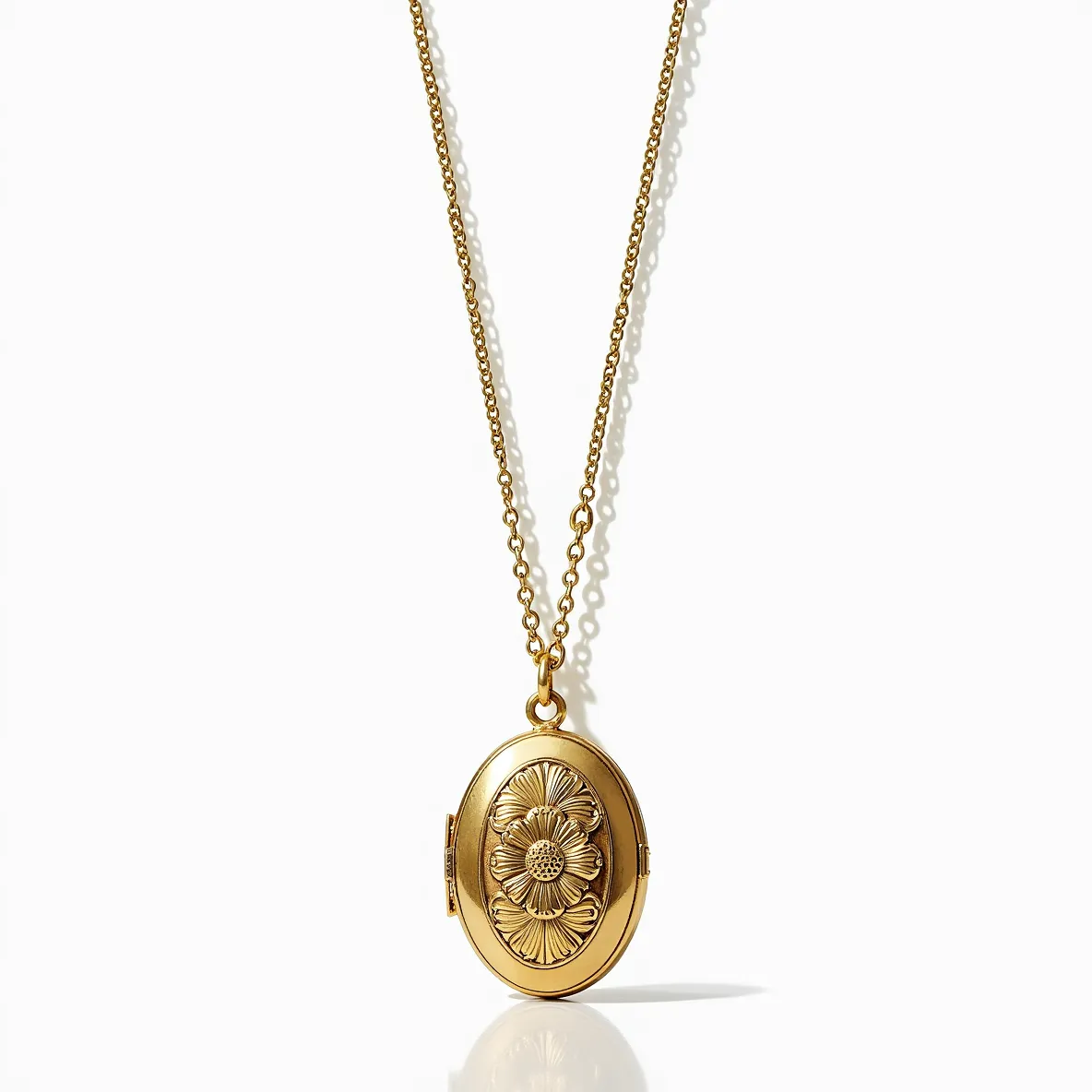 This locket necklace features a gold-toned oval pendant with an intricately designed floral motif on the front. The central flower design incorporates fine detailing that accentuates its elegant appearance, and at the heart of the flower is a small, sparkling gem that appears to be set securely, enhancing the locket's aesthetic appeal. The chain is made of matching gold-toned links, which offer a classic and seamless connection to the pendant. The necklace likely uses a traditional clasp, such as a spring ring or lobster clasp, which ensures secure wear. Overall, the design merges timeless elegance with a touch of personal charm.