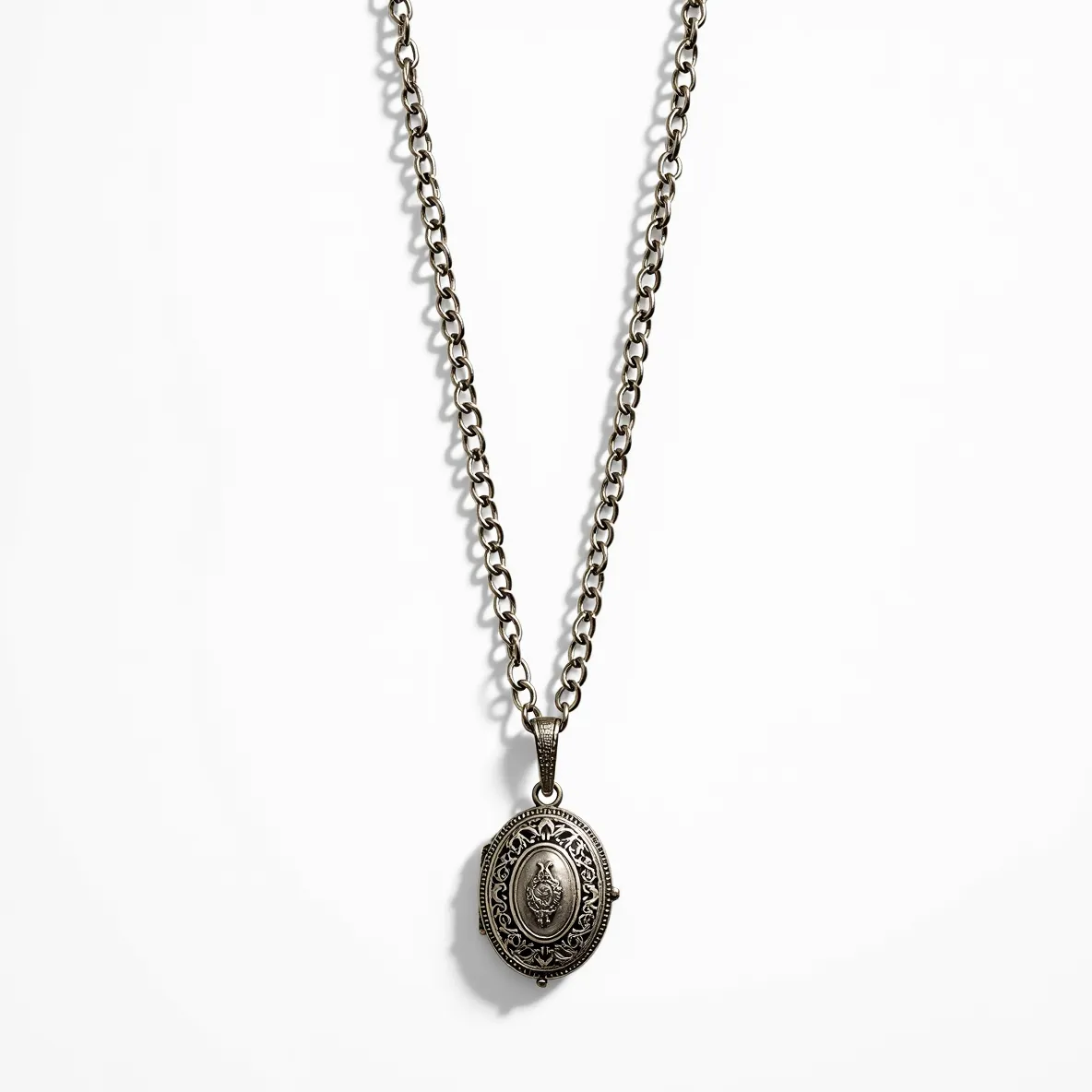 This locket necklace features an intricately designed oval pendant made of a metallic material with a vintage finish. The locket is adorned with detailed engravings that add to its ornate appearance. The chain is composed of a series of interlinked oval links, which are substantial enough to match the bold design of the pendant. The clasp is a traditional lobster claw, ensuring a secure closure. The overall aesthetic is one of antique charm, making it a striking piece of jewelry.