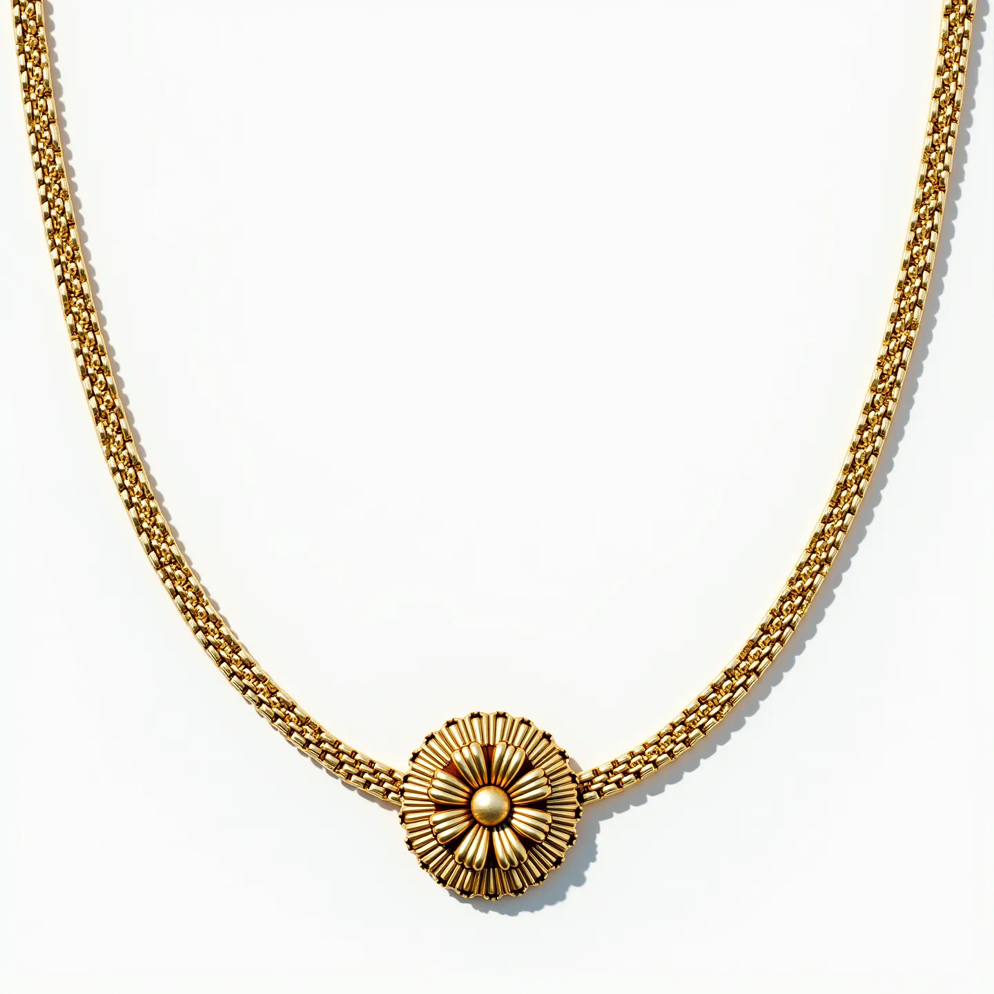 This long gold necklace features a braided chain design, creating a rich and textured appearance. At its center is an ornate circular pendant with a floral motif, boasting petals intricately designed in relief with a polished gold finish. The pendant's inner circle highlights a raised, smooth, rounded element, mimicking a flower's center, enhancing the overall aesthetic. The craftsmanship showcases a sophisticated balance between the chain and pendant, suggesting meticulous attention to detail without visible gemstones or additional materials.