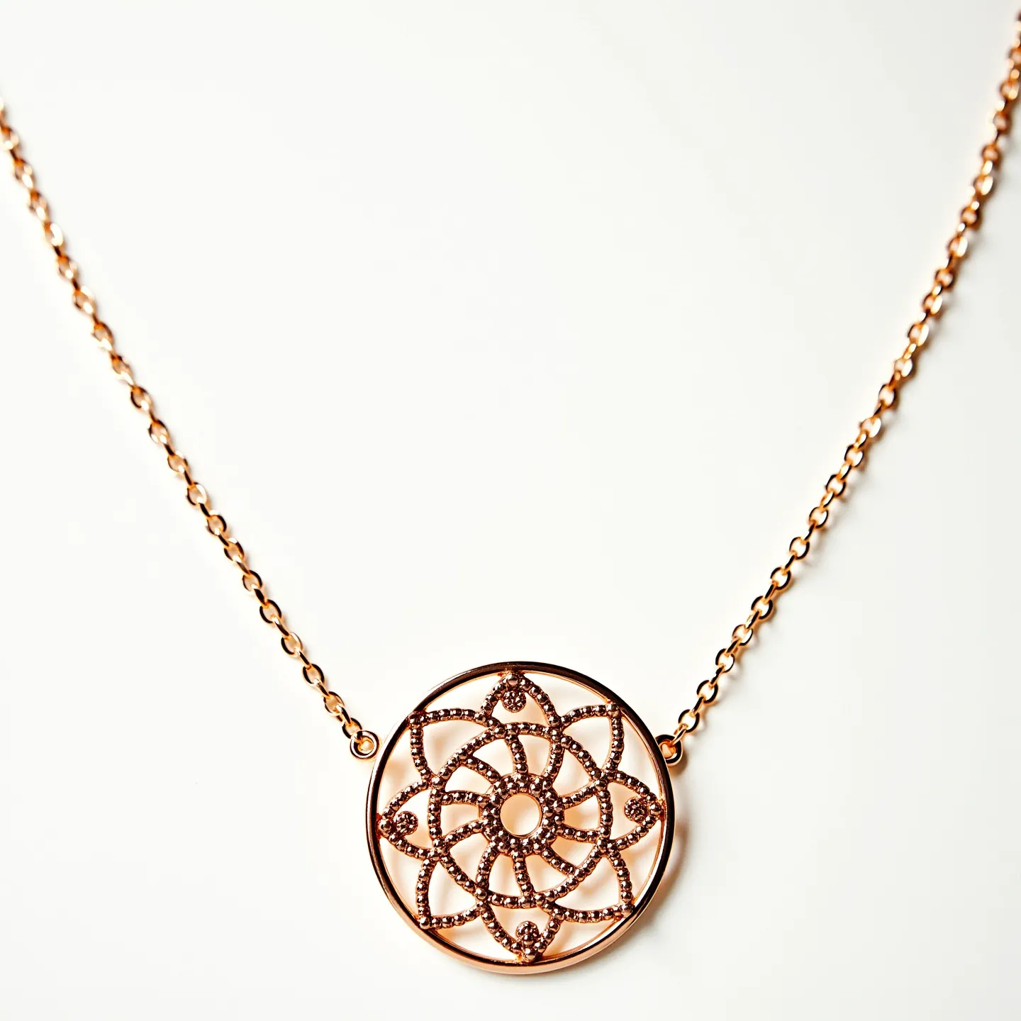 This long gold necklace features a delicate, thin chain that beautifully complements a central pendant. The pendant is an intricate circular design, resembling a floral or mandala pattern, adding a touch of elegance and sophistication. Tiny brown stones, possibly diamonds or cubic zirconia, are embedded within the pattern, enhancing its sparkle and visual appeal. The stones are set in a pavé setting, ensuring they are securely fastened while catching the light from various angles. The necklace likely includes a secure clasp, typical of such designs, to ensure ease of wear and security.