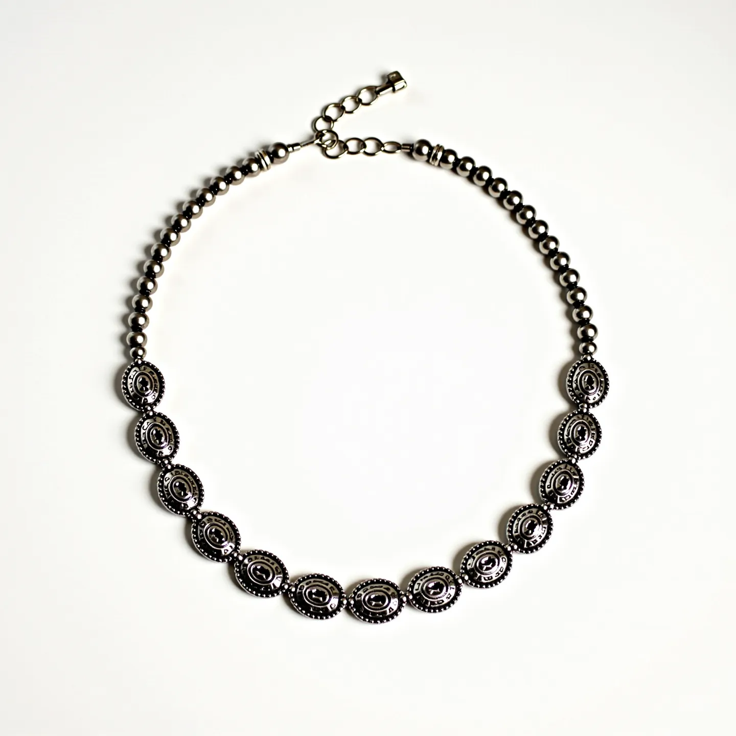 This men's beaded necklace features an alternating pattern of polished, round metallic beads that exude a sleek and modern aesthetic. The central section highlights intricately designed oval beads, each embellished with a symmetrical pattern that adds visual interest and texture. These oval elements seem to be crafted from a durable metal, possibly silver or stainless steel, offering a robust and masculine touch. The necklace is equipped with a practical lobster claw clasp, accompanied by an adjustable chain, allowing for a customizable fit and ensuring ease of wear. Overall, the combination of materials and design elements creates a sophisticated accessory suitable for various occasions.