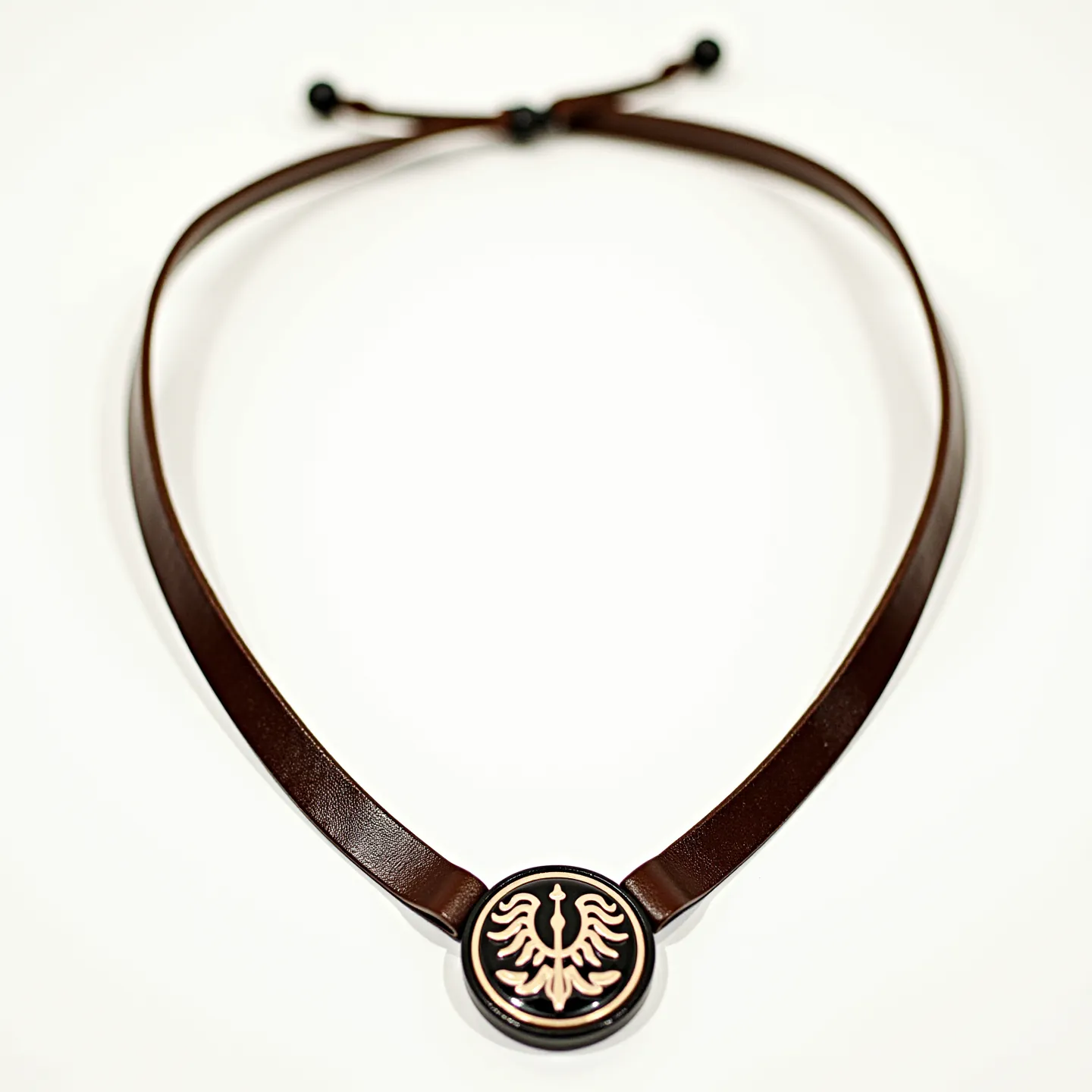 This men's necklace features a leather cord in a rich brown hue, enhanced by a central round pendant. The pendant showcases an embossed design of an eagle with outstretched wings, executed in a contrasting gold tone against a black background. The necklace employs a slide knot mechanism for adjustment, allowing for a secure and customizable fit.