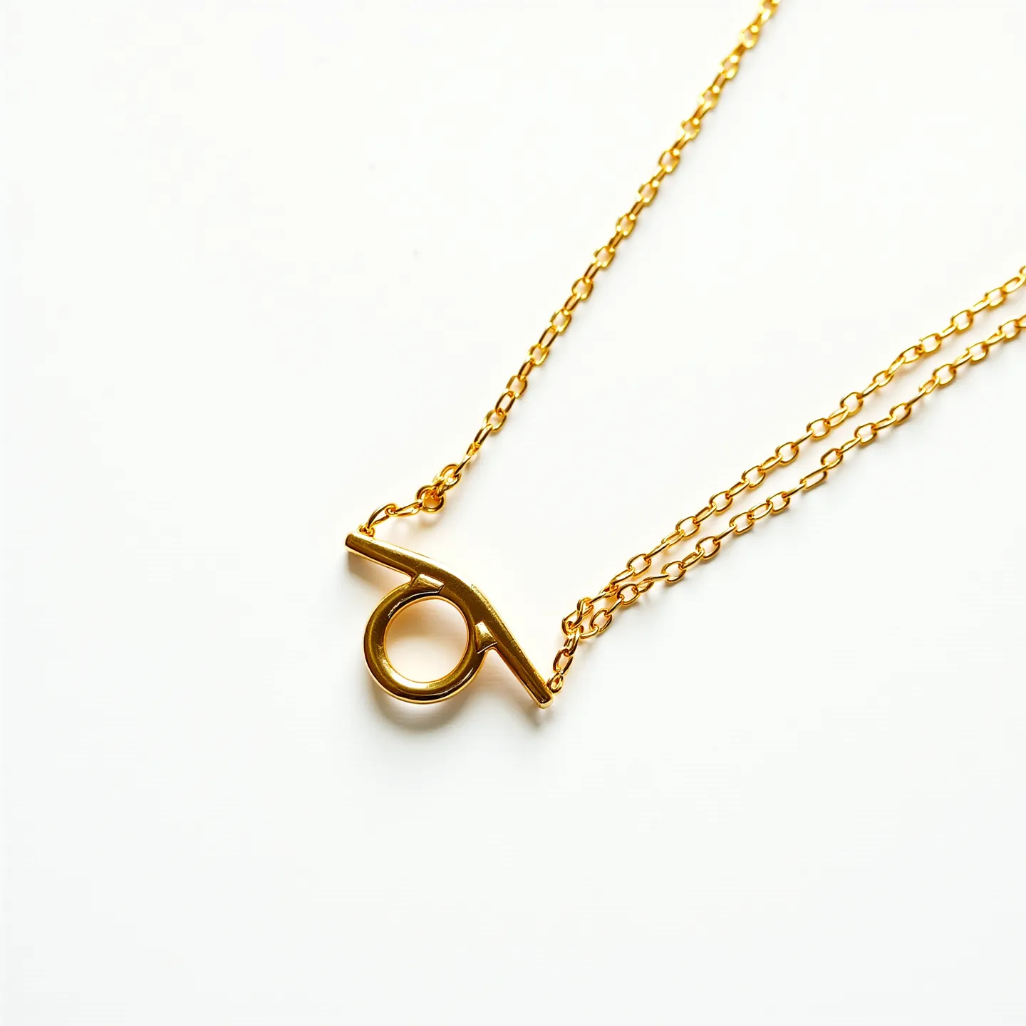 This men's necklace features a delicate gold chain made of polished metal, offering a bright and sleek appearance. The focal point is a simple yet elegant toggle clasp design at the center, comprising a circular ring and a horizontal bar. This functional and stylish clasp serves as both the closure and a decorative element, emphasizing minimalistic sophistication. The chain links are small and uniform, contributing to a refined and modern aesthetic.