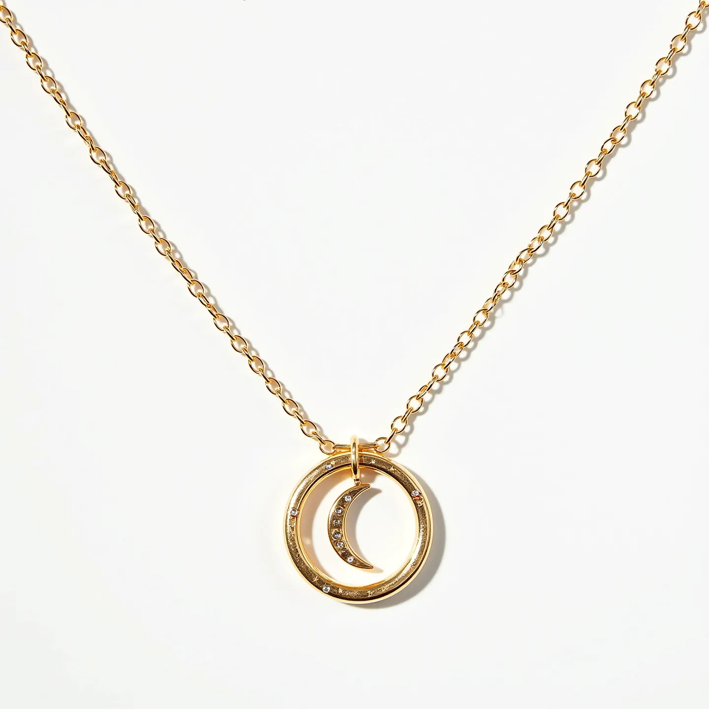 This celestial moon necklace features a delicate gold chain, which suspends a dual pendant design comprising a crescent moon nested within a circular frame. Both the crescent and the circular frame are adorned with small, sparkling gemstones, potentially diamonds or cubic zirconia, that are subtly embedded into the gold-toned material. The gems are cut to catch the light, enhancing the necklace's overall elegance. The pendant is attached to the chain by a small loop, allowing it to hang freely. The necklace likely uses a standard spring ring or lobster clasp mechanism to secure it around the neck, ensuring both style and functionality.