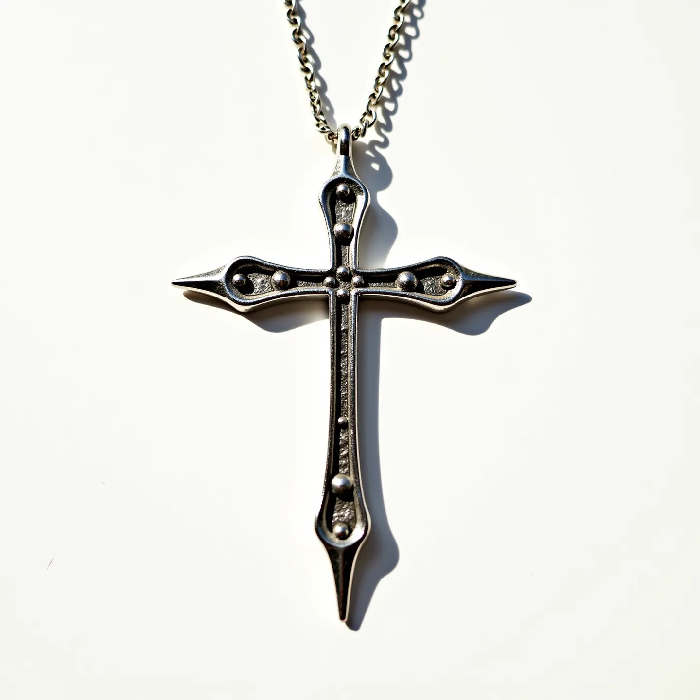 This nail cross necklace features a striking design composed of dark metal, likely stainless steel or a similar alloy, giving it a robust and durable appearance. The cross is crafted to resemble two metallic nails intersecting, emphasizing the rugged aesthetic. Each nail end is rounded, which adds a unique stylistic element to the overall piece. The necklace is equipped with a chain that seems to be made of the same metal, creating a cohesive look. There are no discernible gemstones set within the piece, maintaining the focus on the metalwork. The necklace includes a straightforward chain link attachment, allowing easy wear.